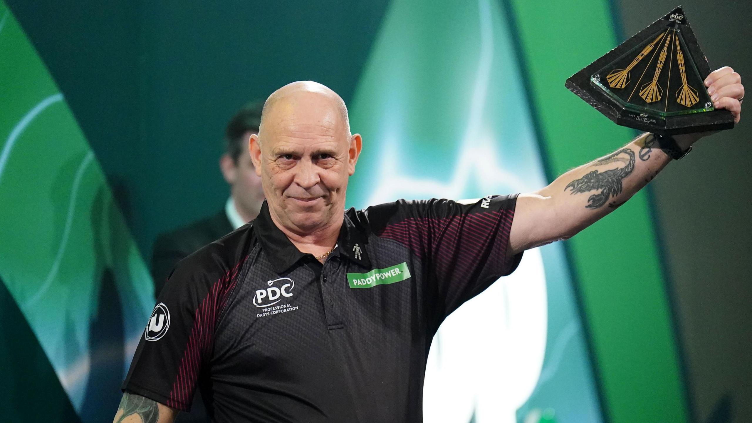 Russ Bray is holding up a trophy as he is inducted into the PDC Darts Hall of Fame prior to the final of the Paddy Power World Darts Championship at Alexandra Palace in January