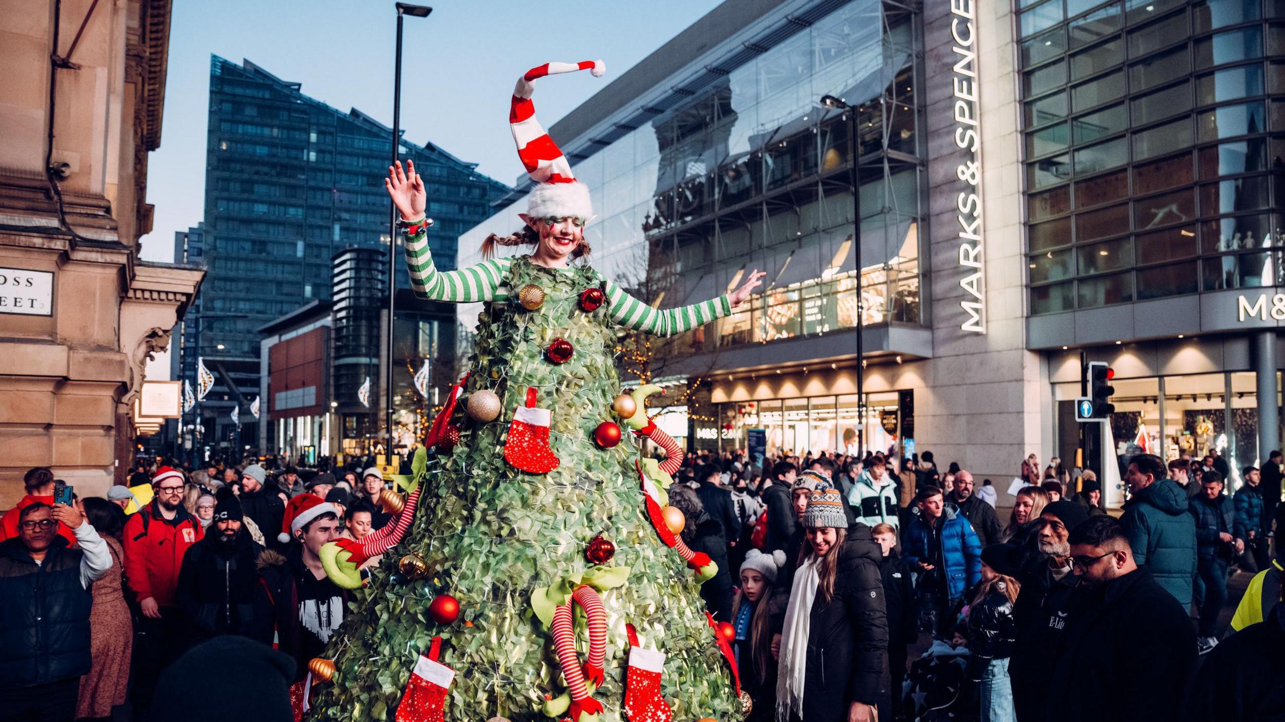 A woman dressed up as a Christmas tree on stilts for a Christmas Parade in Manchester city centre with hundreds of people lining the streets.