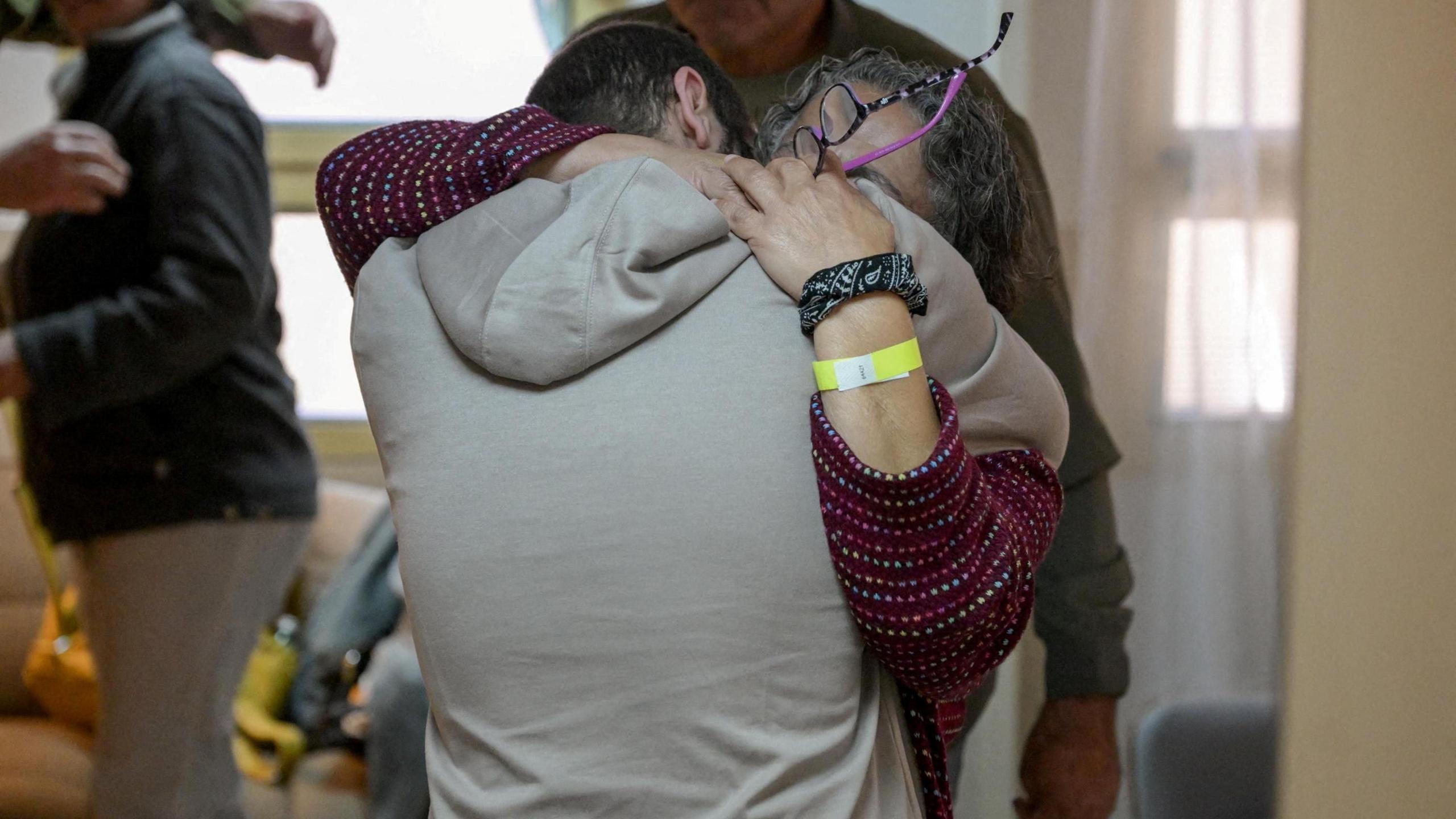 Yarden Bibas is reunited with his loved ones at Sheba Medical Center in Ramat Gan, Israel. He wears a grey hoodie and has his back to the camera as he hugs a family member. 