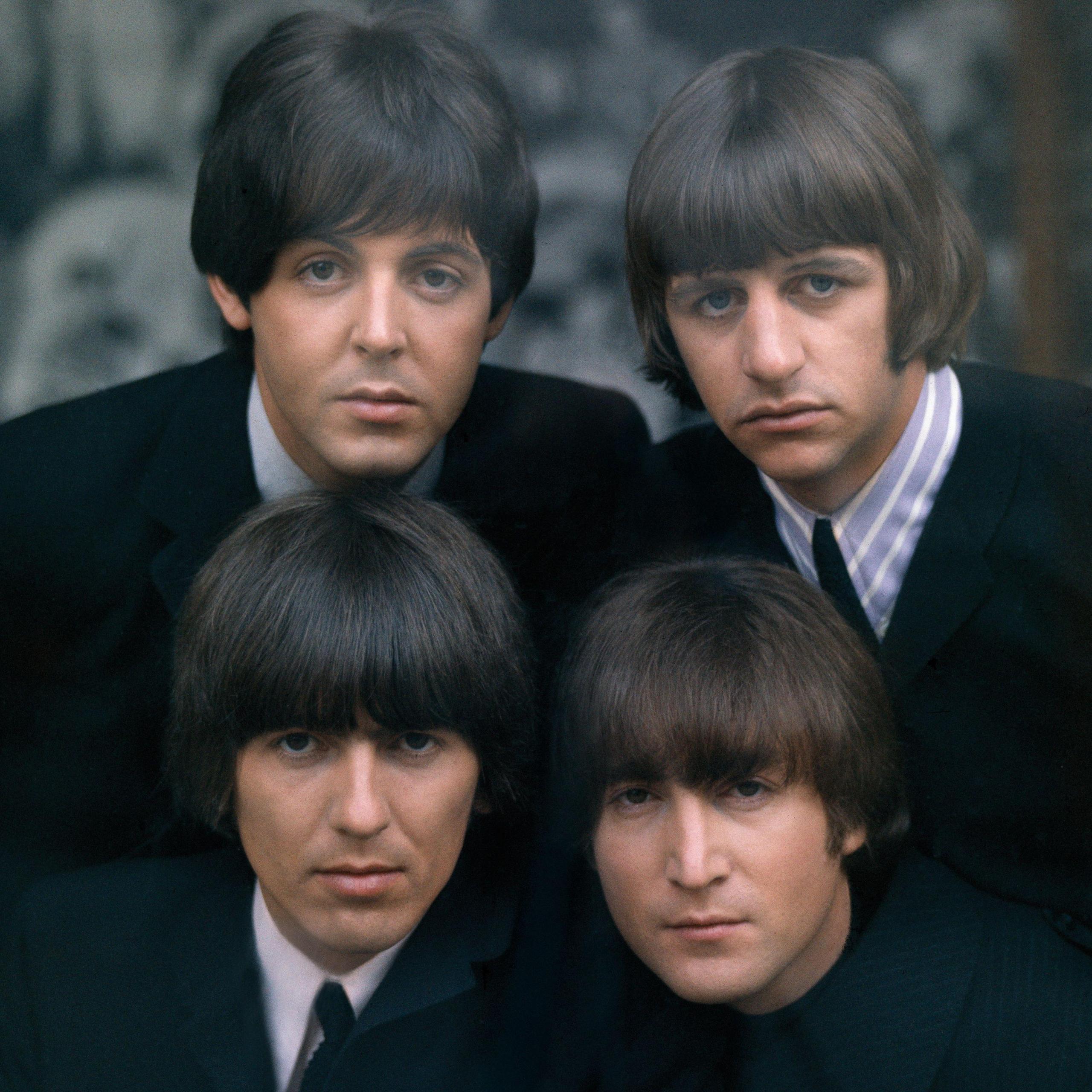 A picture of the Beatles - the four of them appear as young men wearing black suits and look at the camera. 