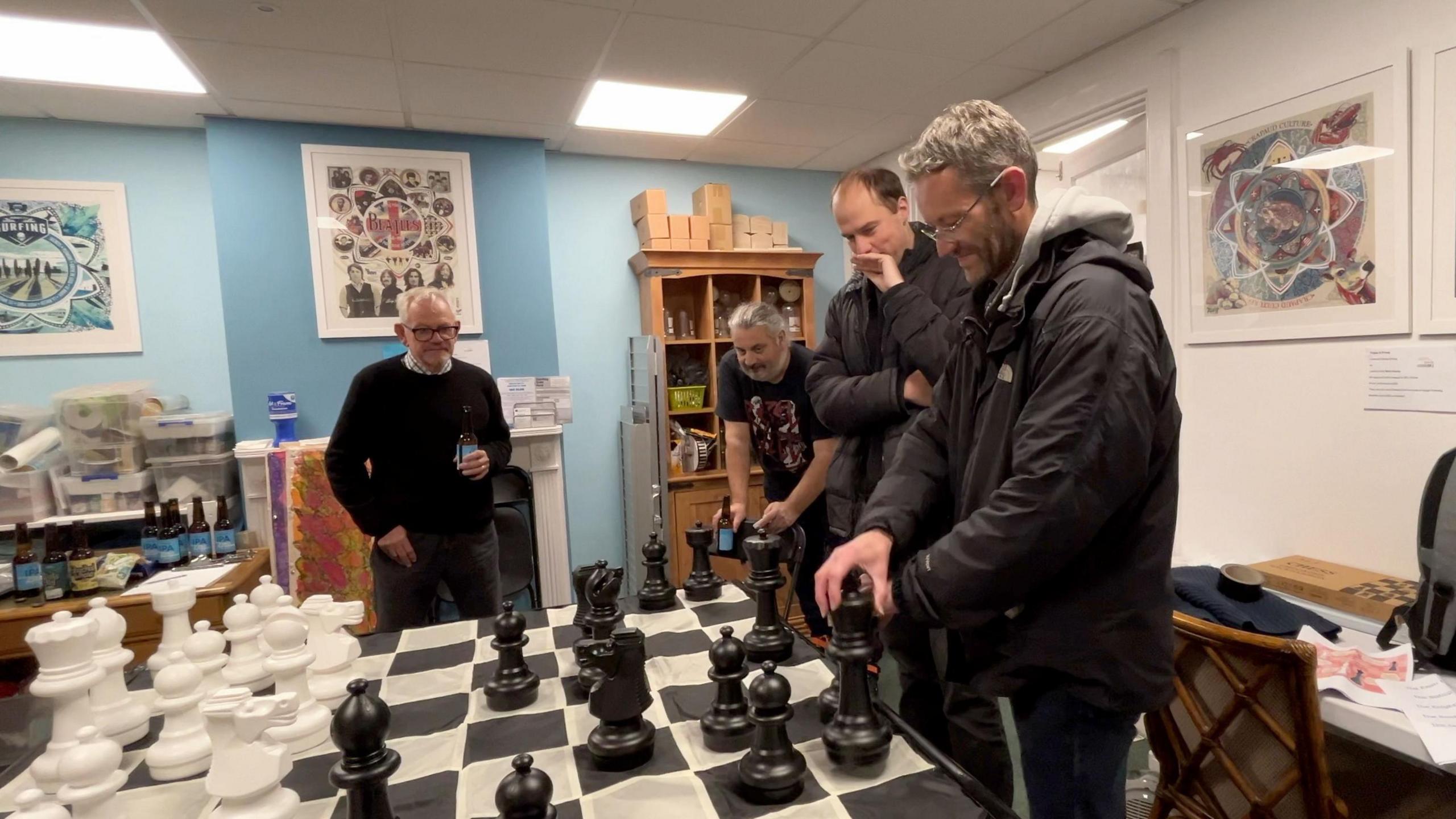 Men play chess on a large board together 