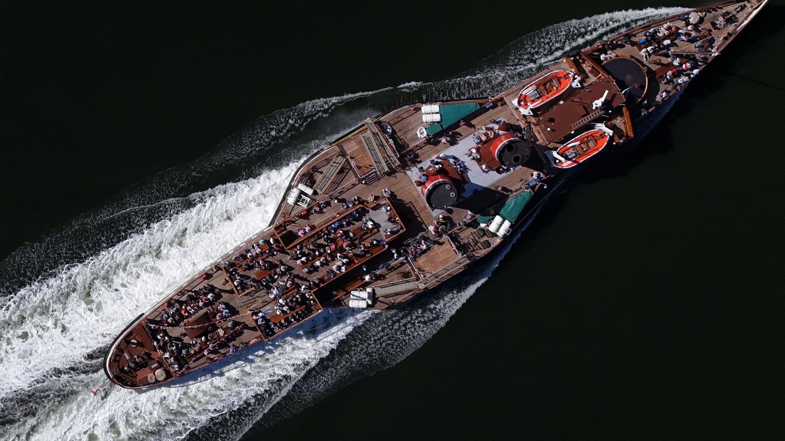 Birds-eye-view of the Waverley, sailing across the ocean with lots of passengers on deck. 