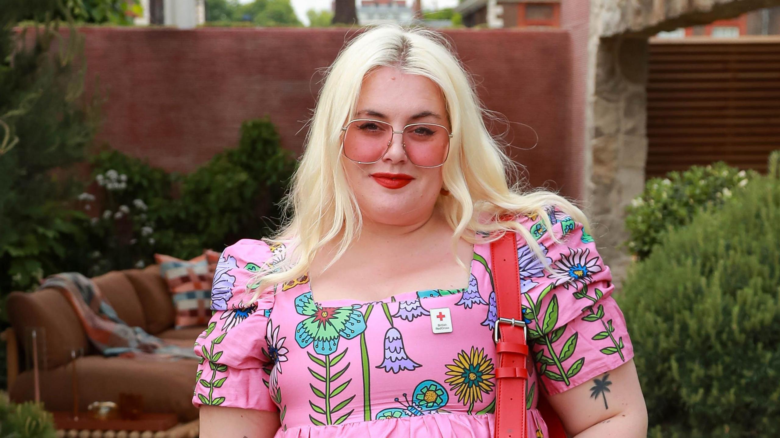 Blonde woman wearing pink sunglasses and a pink dress