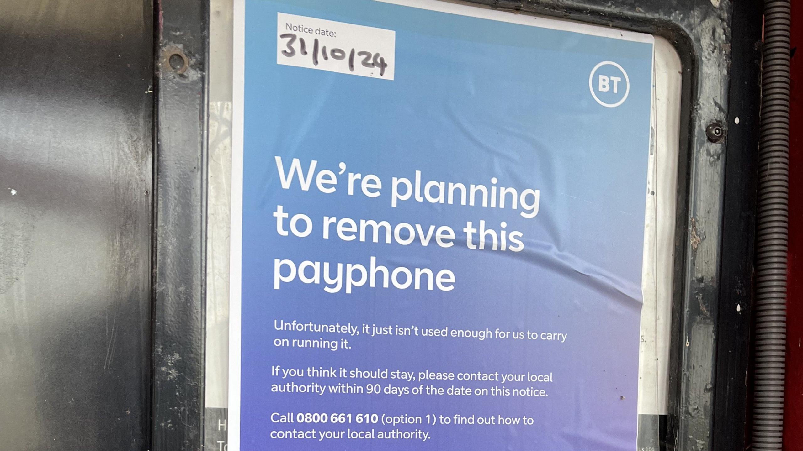 Purple notice with white writing inside the phone box reads: "We're planning to remove this payphone. Unfortunately, it just isn't used enough for us to carry on running it." It invites people who object to contact their local authority within 90 days of the date on the notice, 31/10/24.