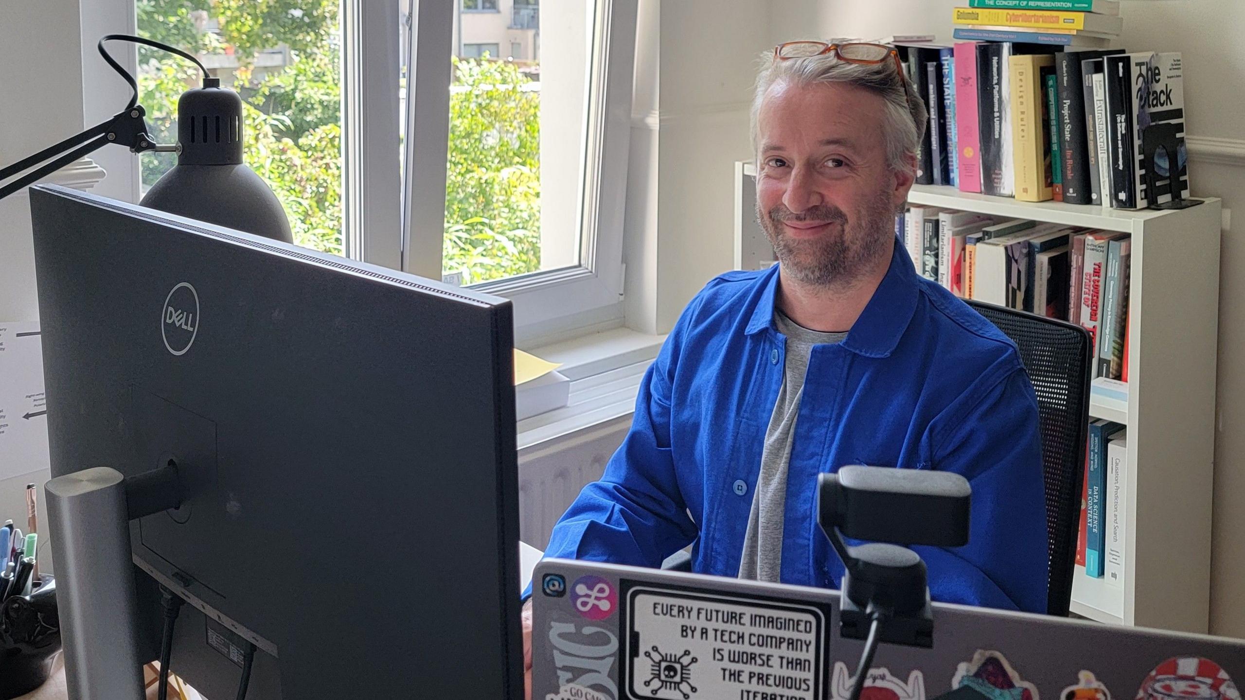 Robin Berjon, a digital governance specialist, smiles at the camera as he sits at his computer in his home office