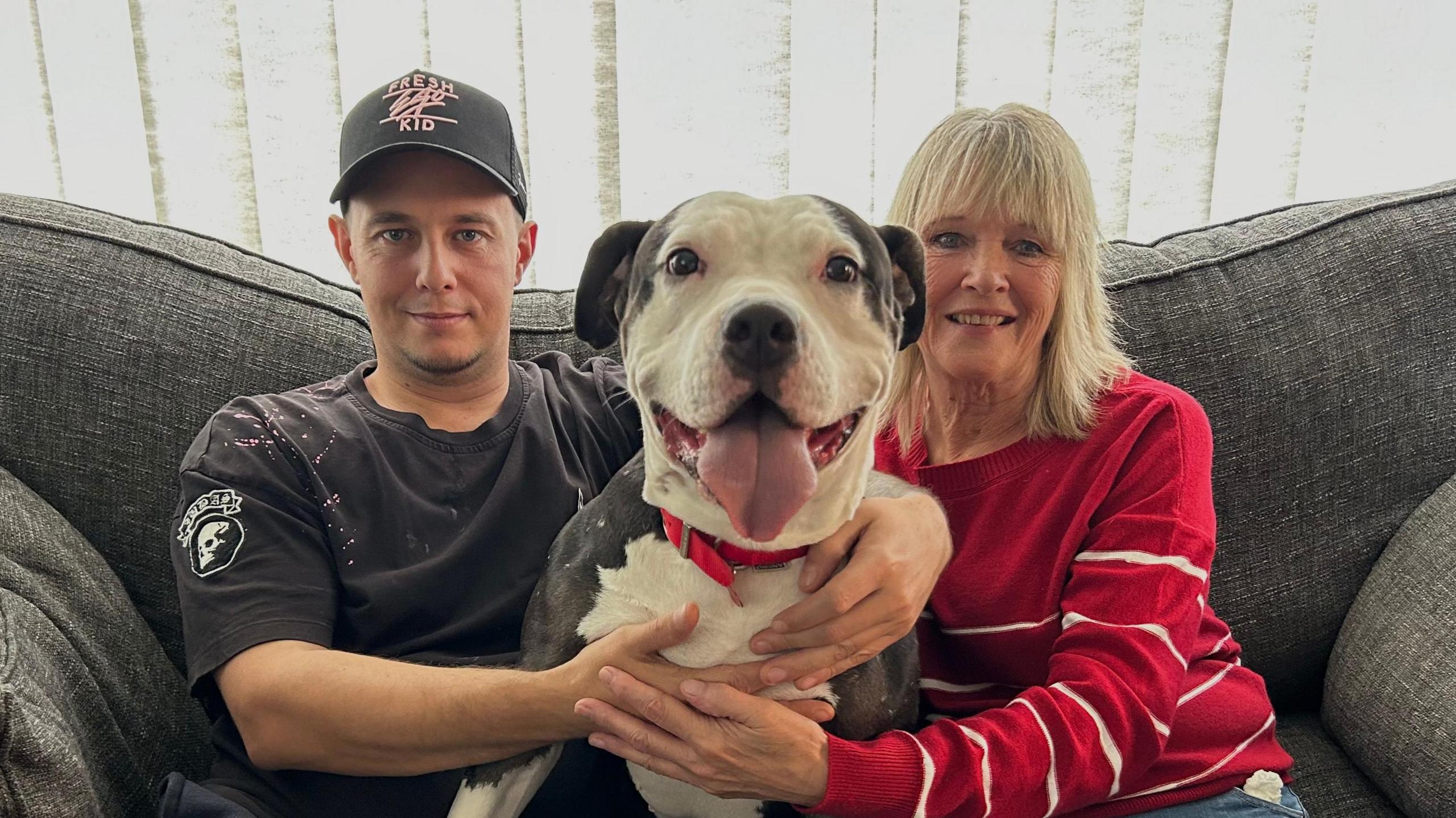 Jareth and Alison sitting on a sofa with American bulldog Nina sat in between them. 