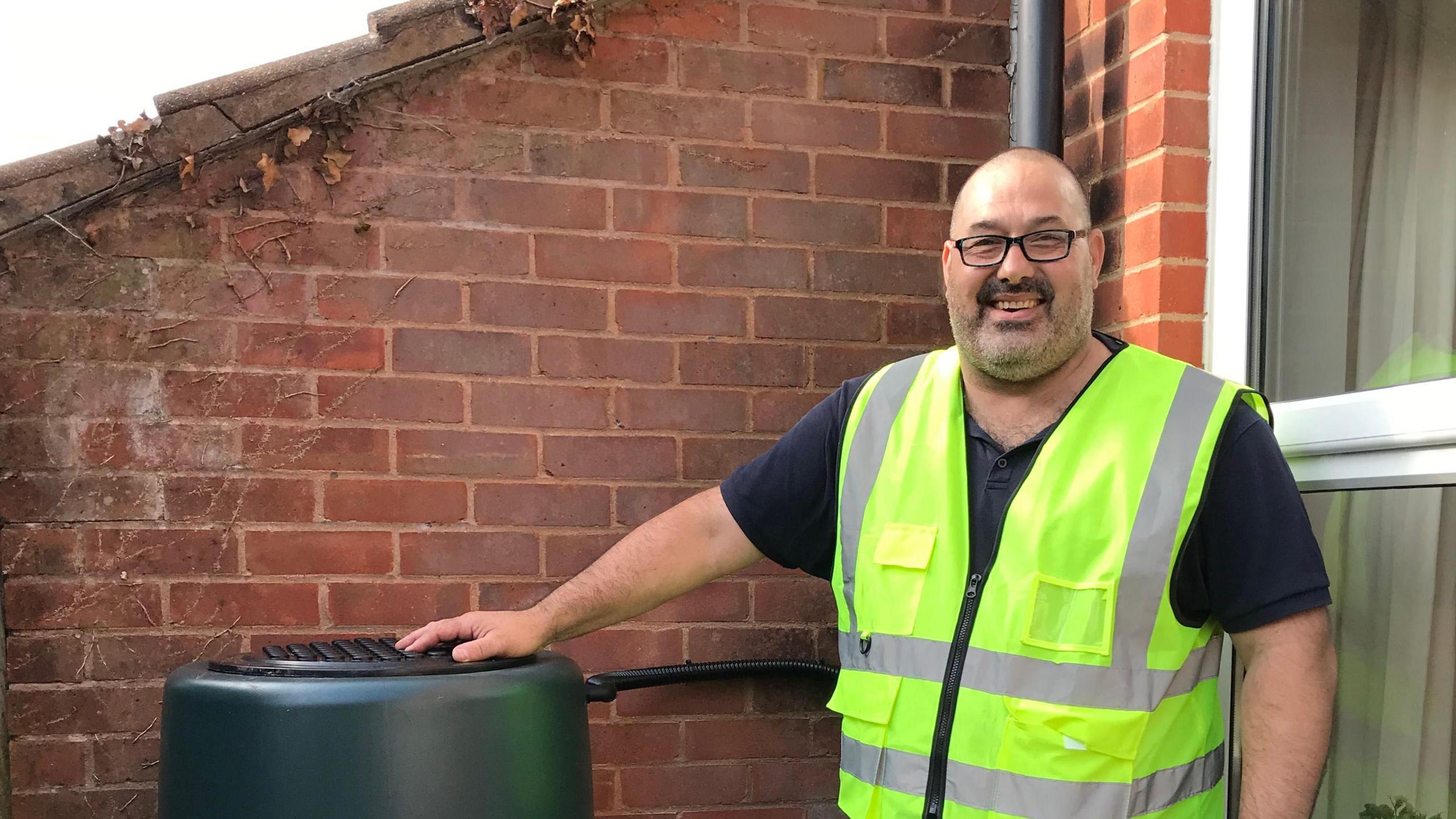 A water butt installer from Save Water to Save the Trym smiles next to an installed water butt