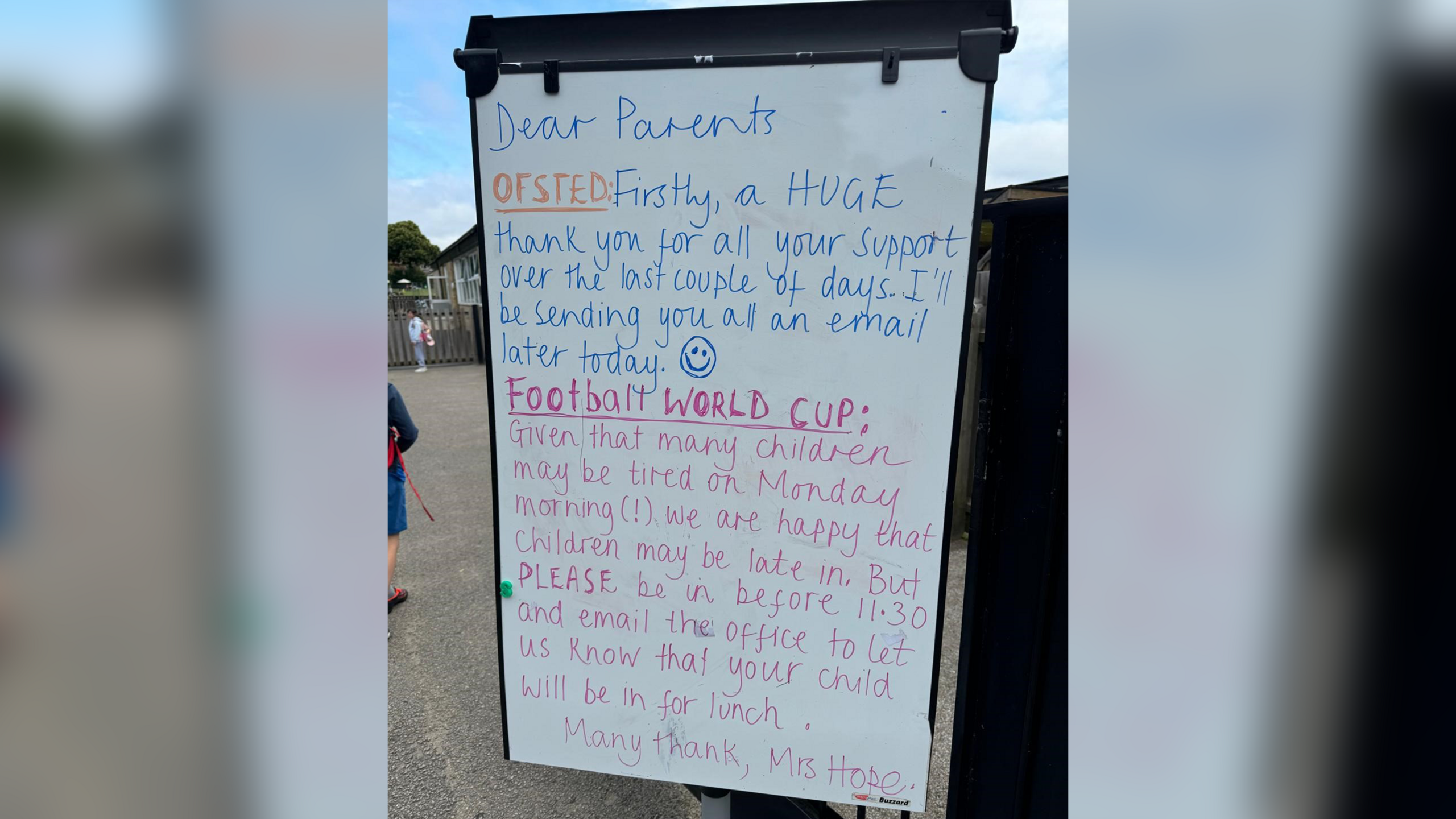 A whiteboard outside the school with information about Monday's school times