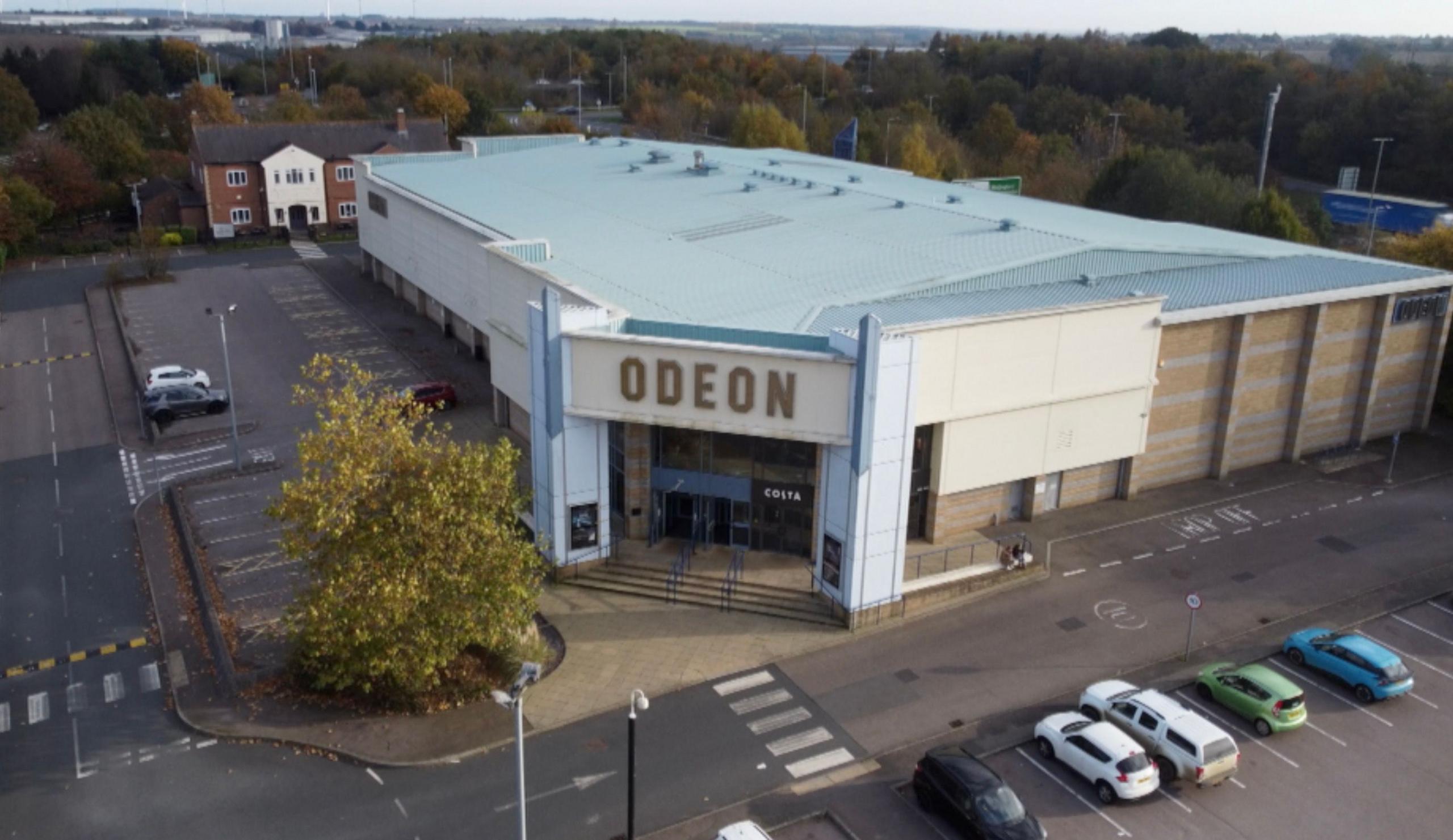 A drone shot of the Odeon building with cars parked outside.