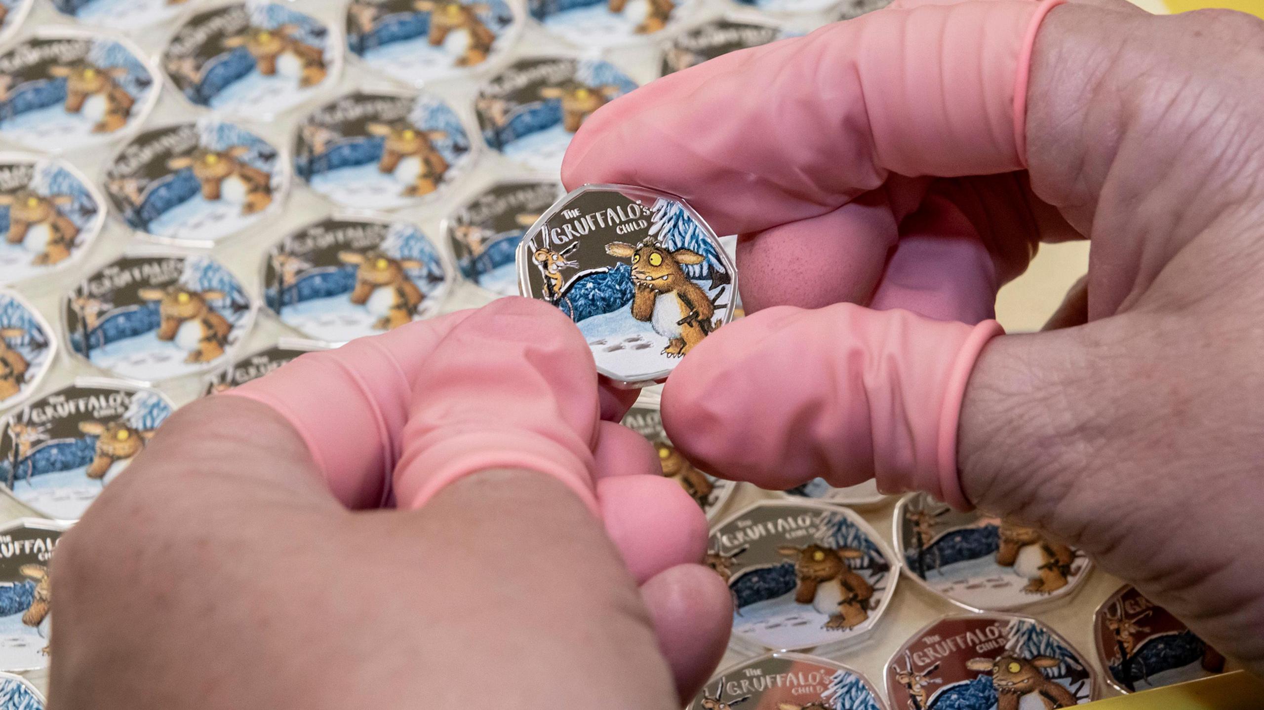 Hands holding colour design of The Gruffalo's Child 50p commemorative coin