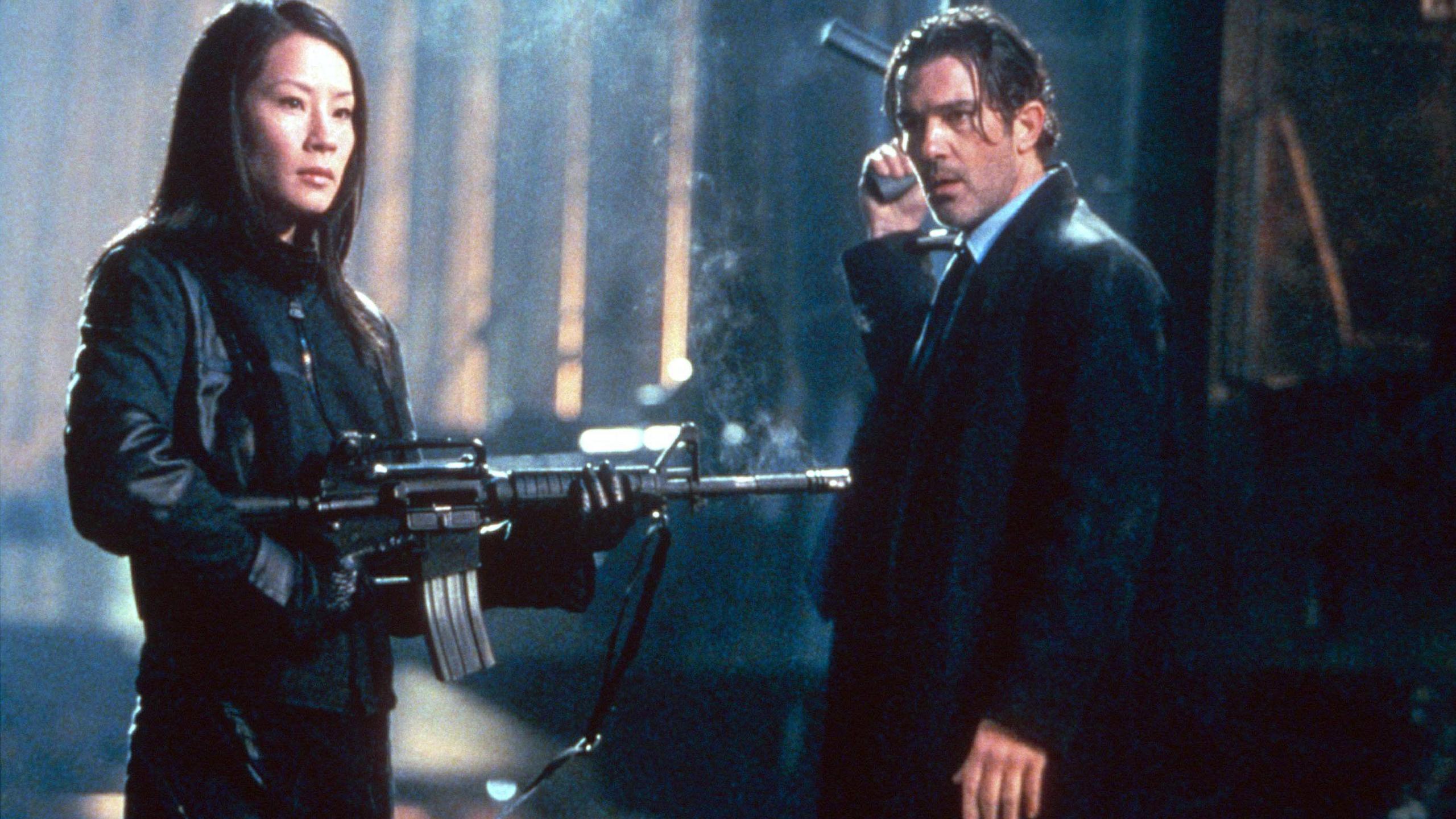 Lucy Liu and Antonio Banderas both standing wearing all black and holding guns in a scene from Ballistic: Ecks vs Sever
