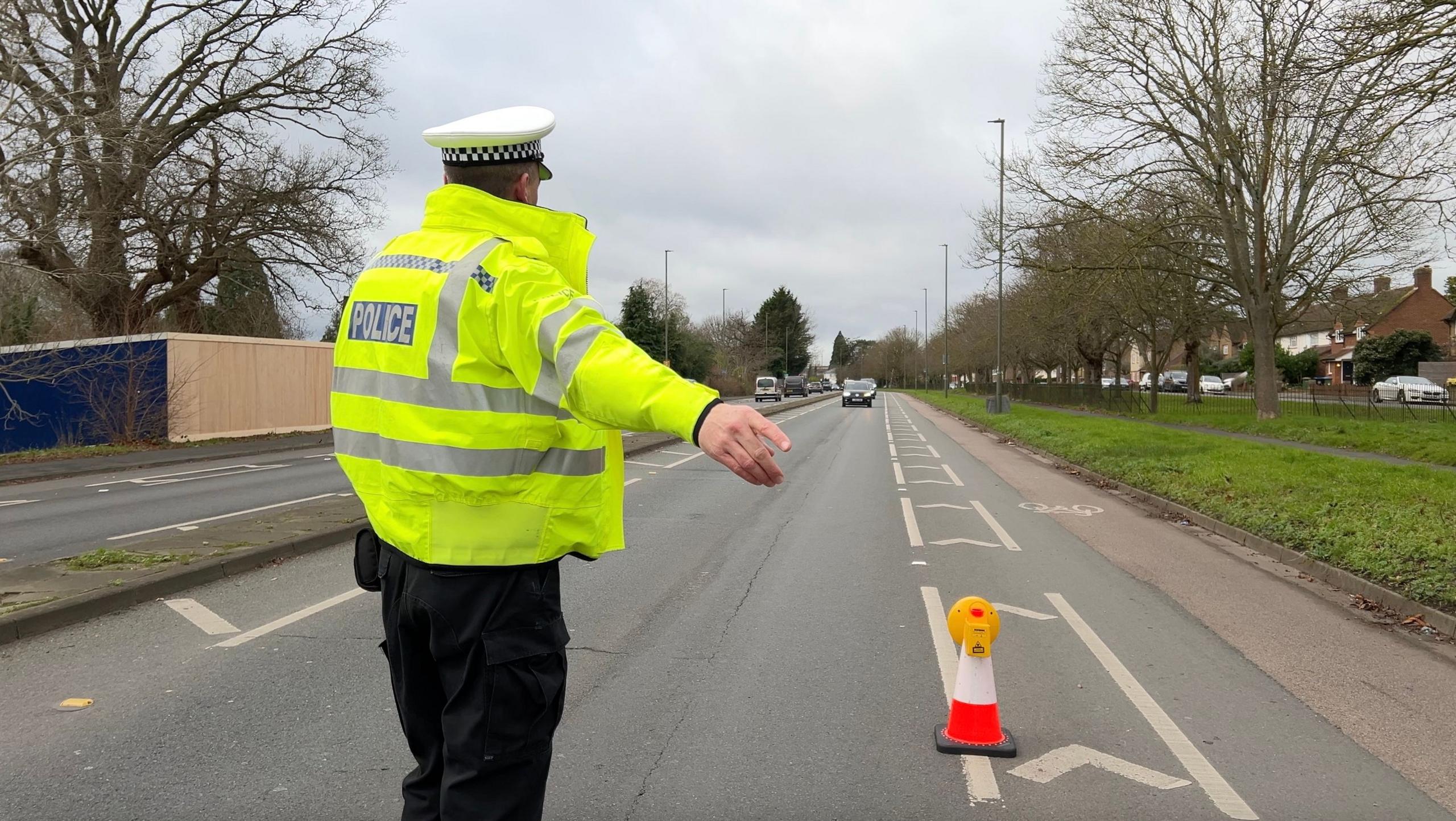 A police officer waves a car to stop at a designated stop site.