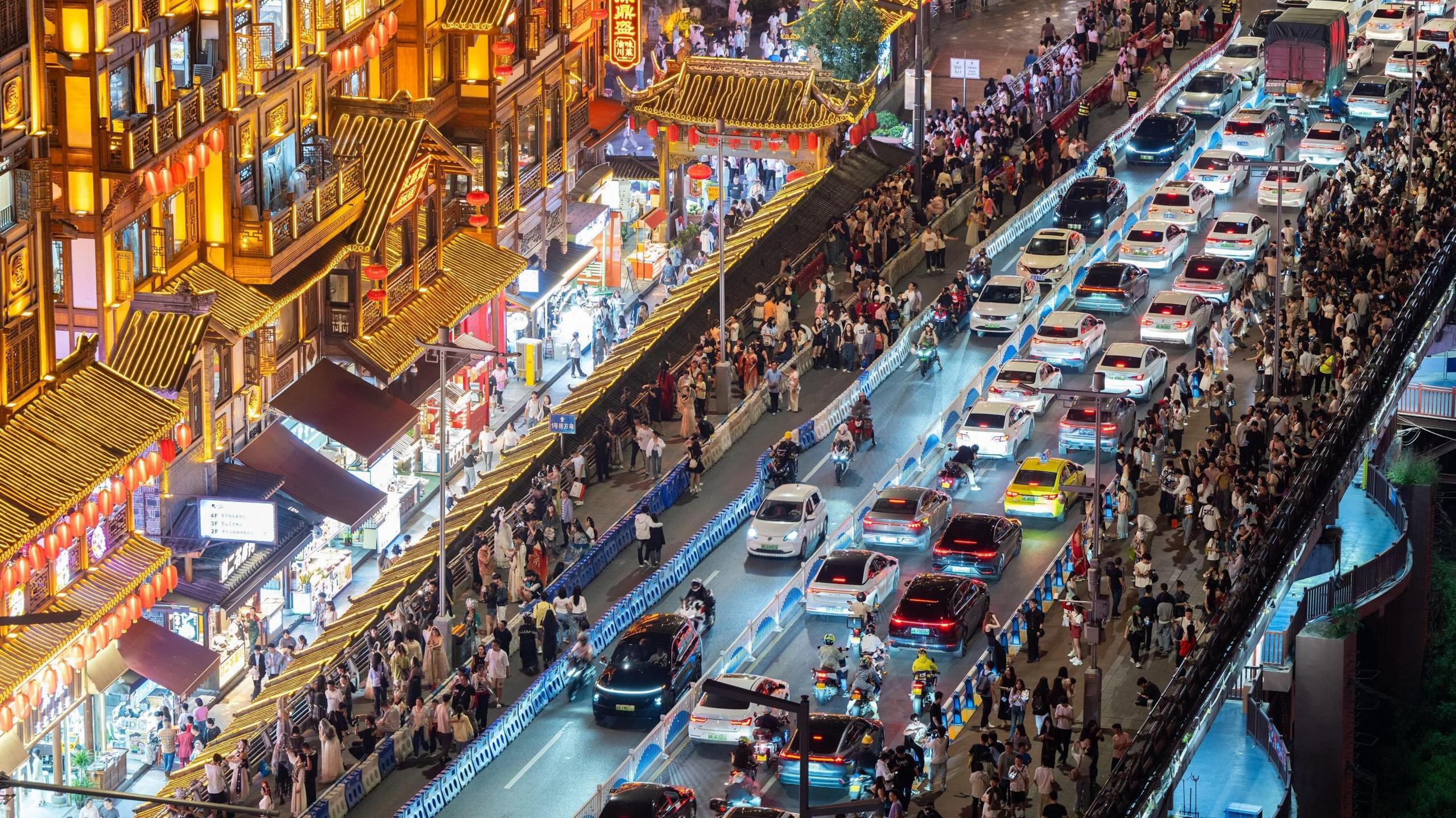 Overhead night-time view of part of Chongqing, with lots of lights, rooftops and people