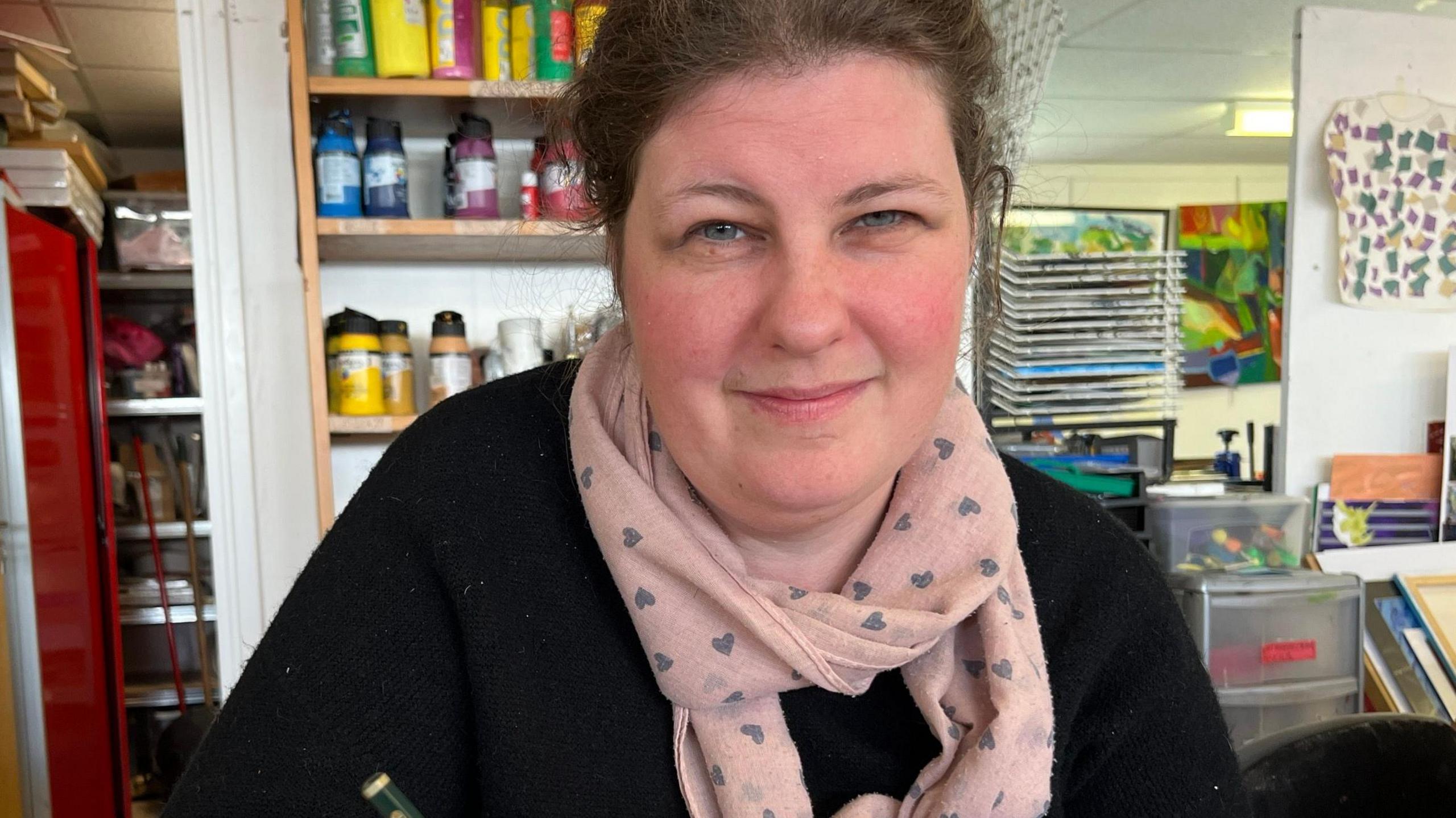  A woman dressed in black with a pink scarf in the Artventure studio.