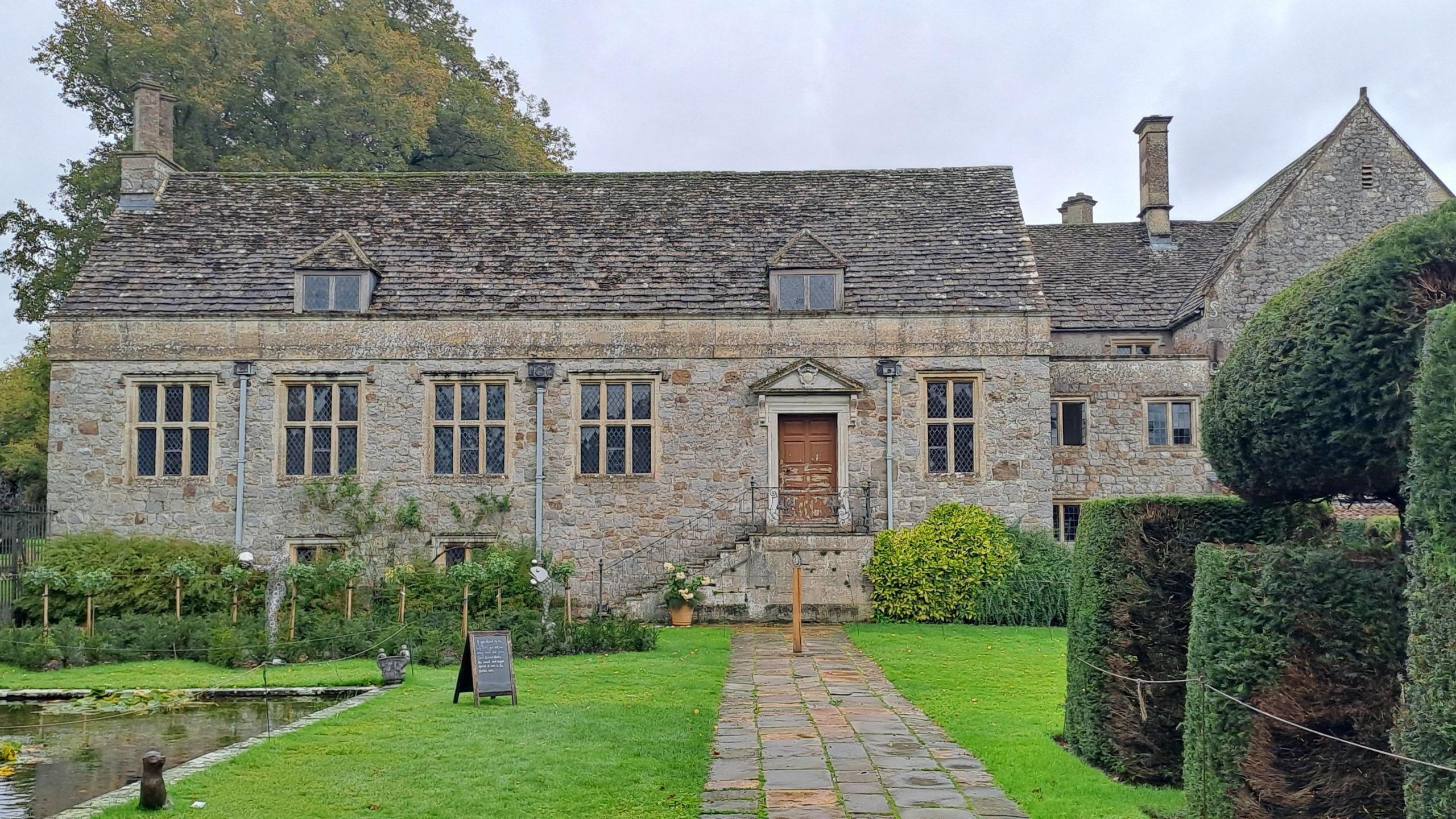 Image of Avebury Manor West Library with gardens in front and a hedge on the right side.