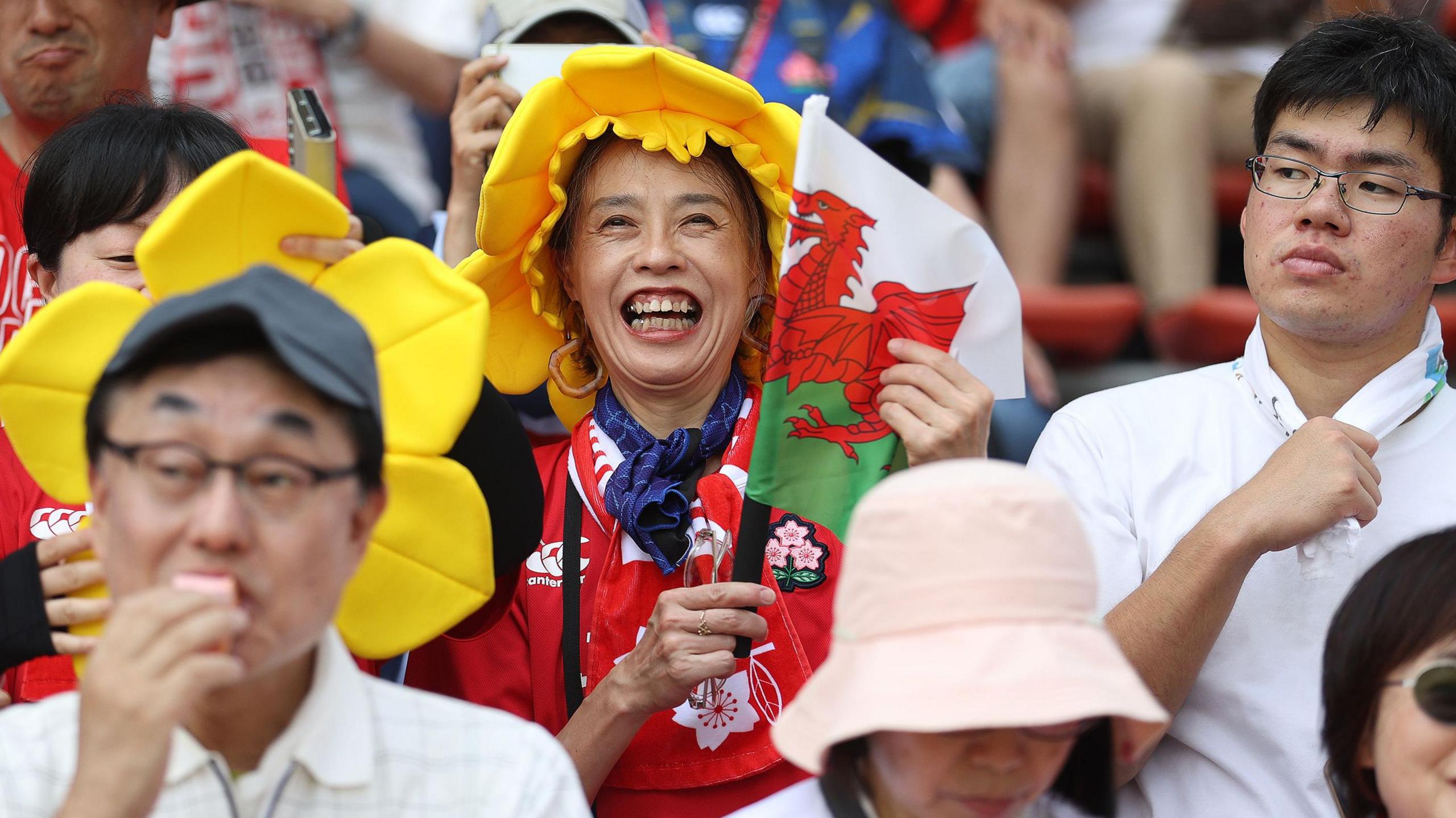 Japan fan smiles with a Wales daffodil hat on