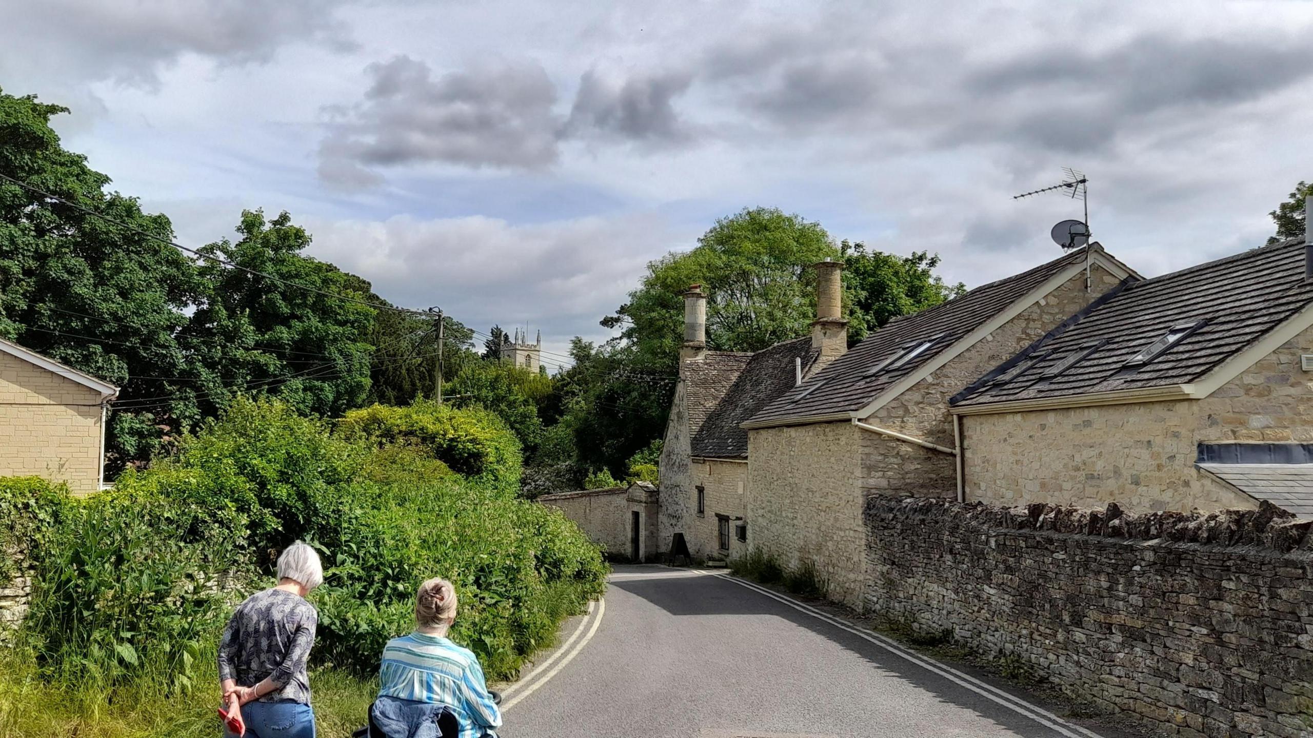 WEDNESDAY - A narrow street with double-yellow lines at either side, lined by stone walls and homes on the right side and green bushes on the left. Taken inNorth Hinksey