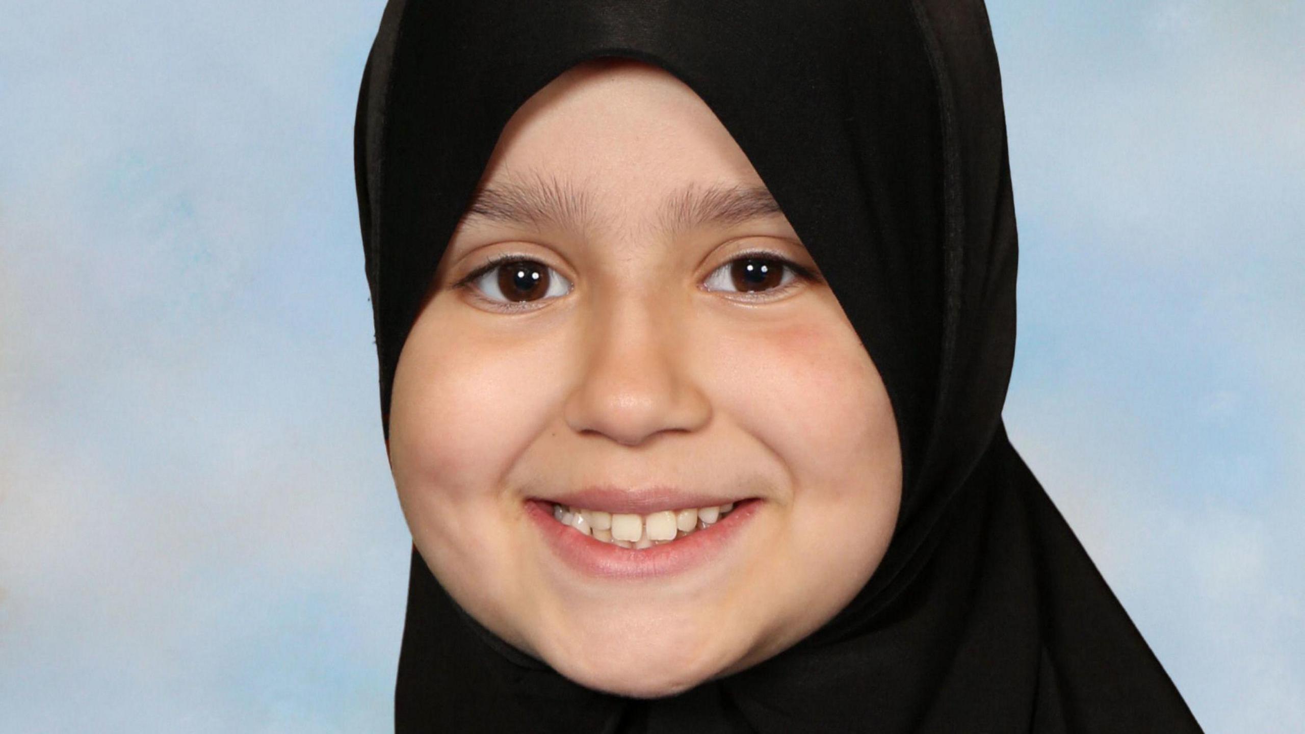 A young girl with a black hijab covering her hair.