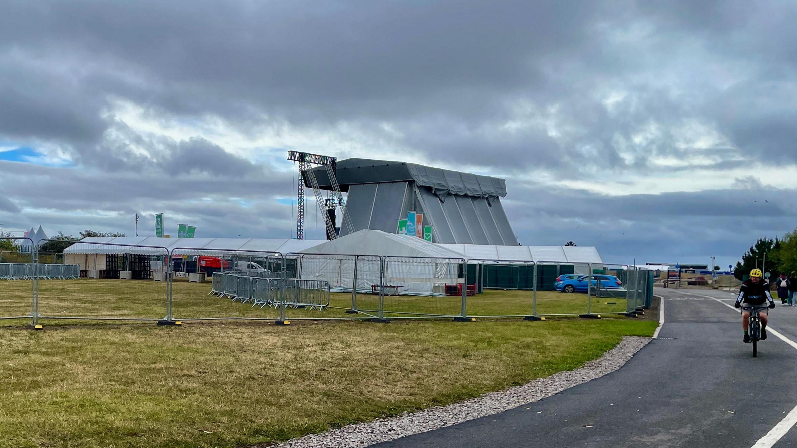 Stage in Cardiff Bay where New Order due to play, with a cyclist passing on a nearby road