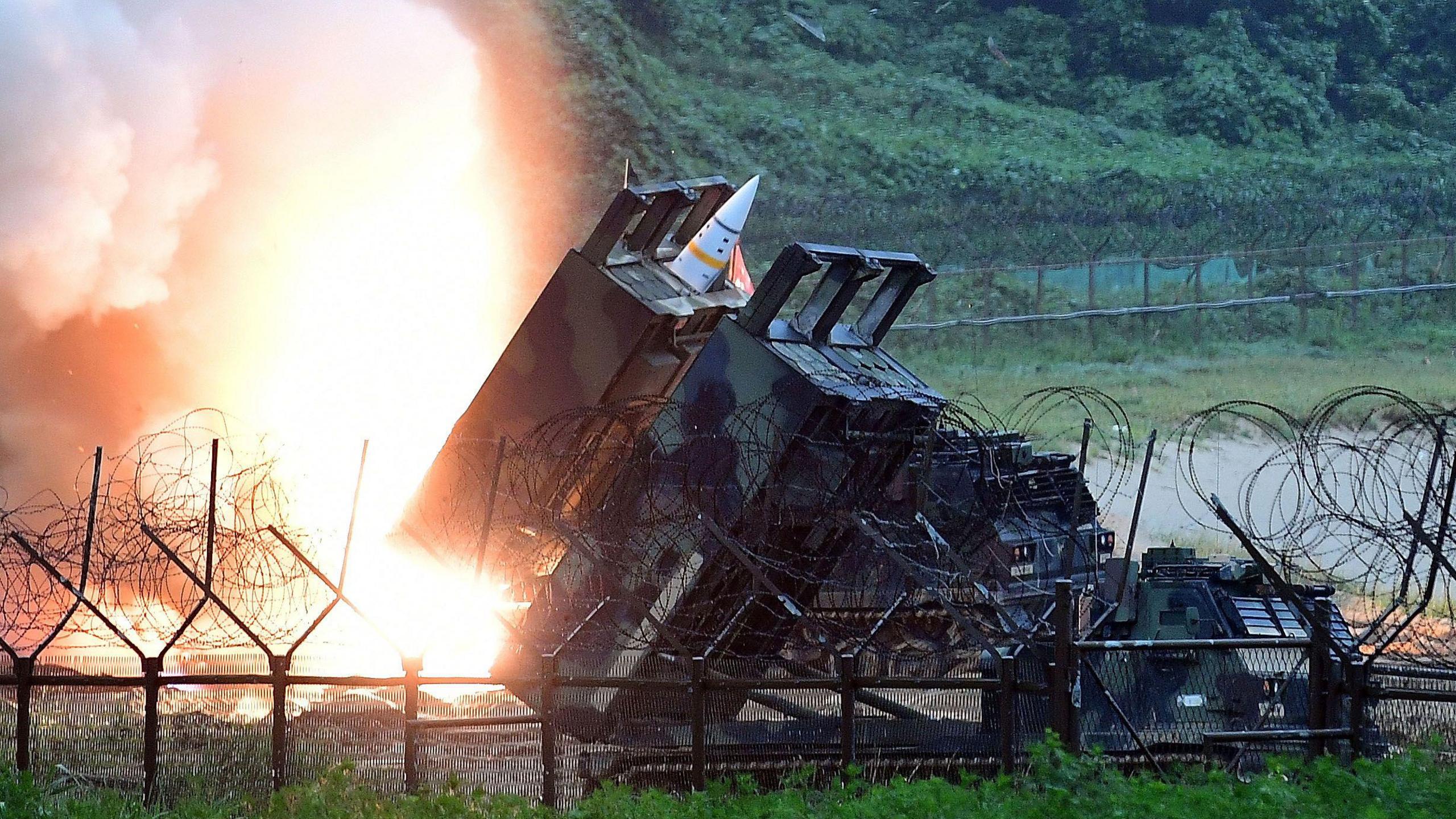 ATACMS missiles are seen during South Korea-US military exercises, surrounded by barbed wire fencing and lush greenery in the background. 