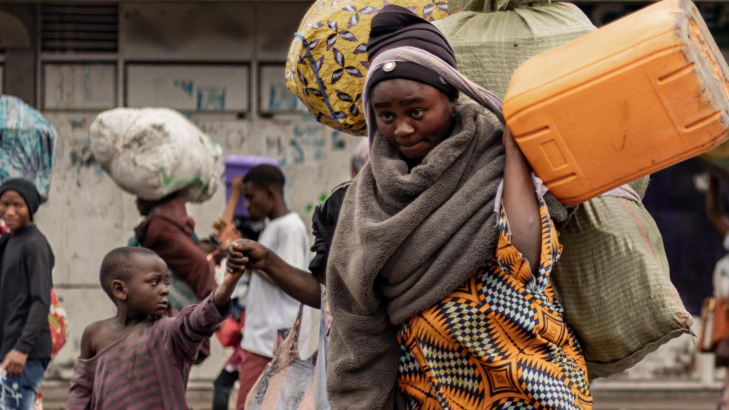 A woman and a child flee with their belongings on their back