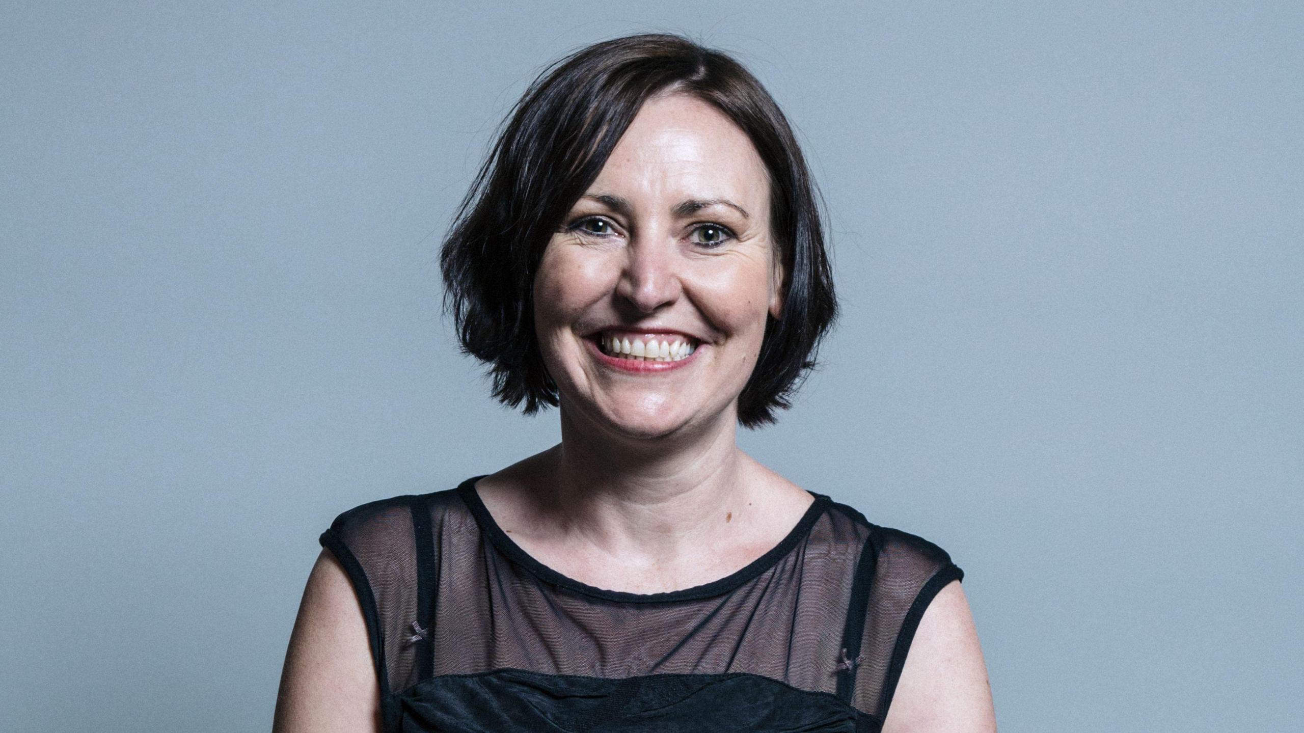 Vicky Foxcroft in her official portrait, smiling at the camera and wearing a dark top. She has short brown hair.