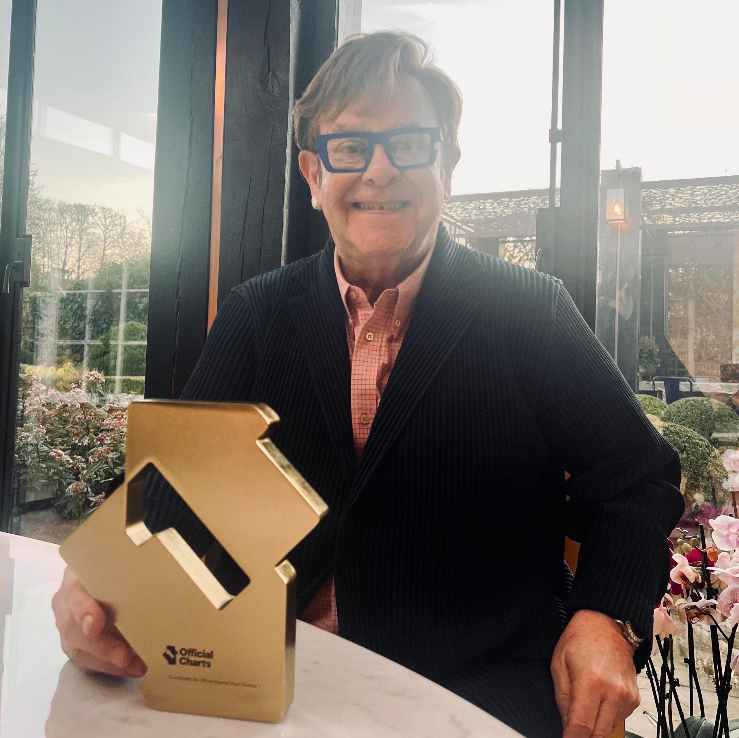 Elton John poses with his Official Charts number one award