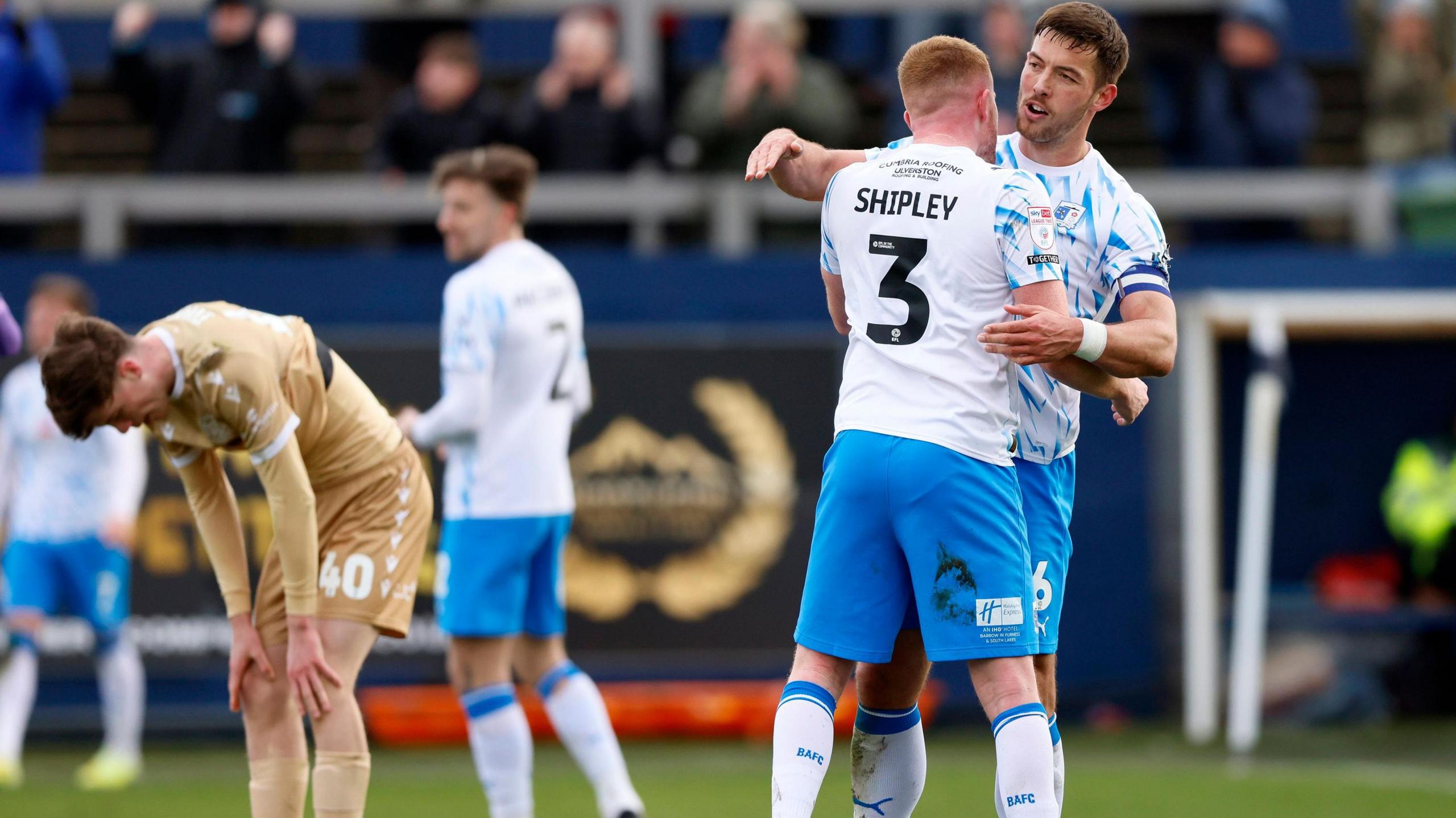 Barrow's Lewis Shipley and Barrow's Niall Canavan celebrate, while Bromley's George Evans looks dejected.