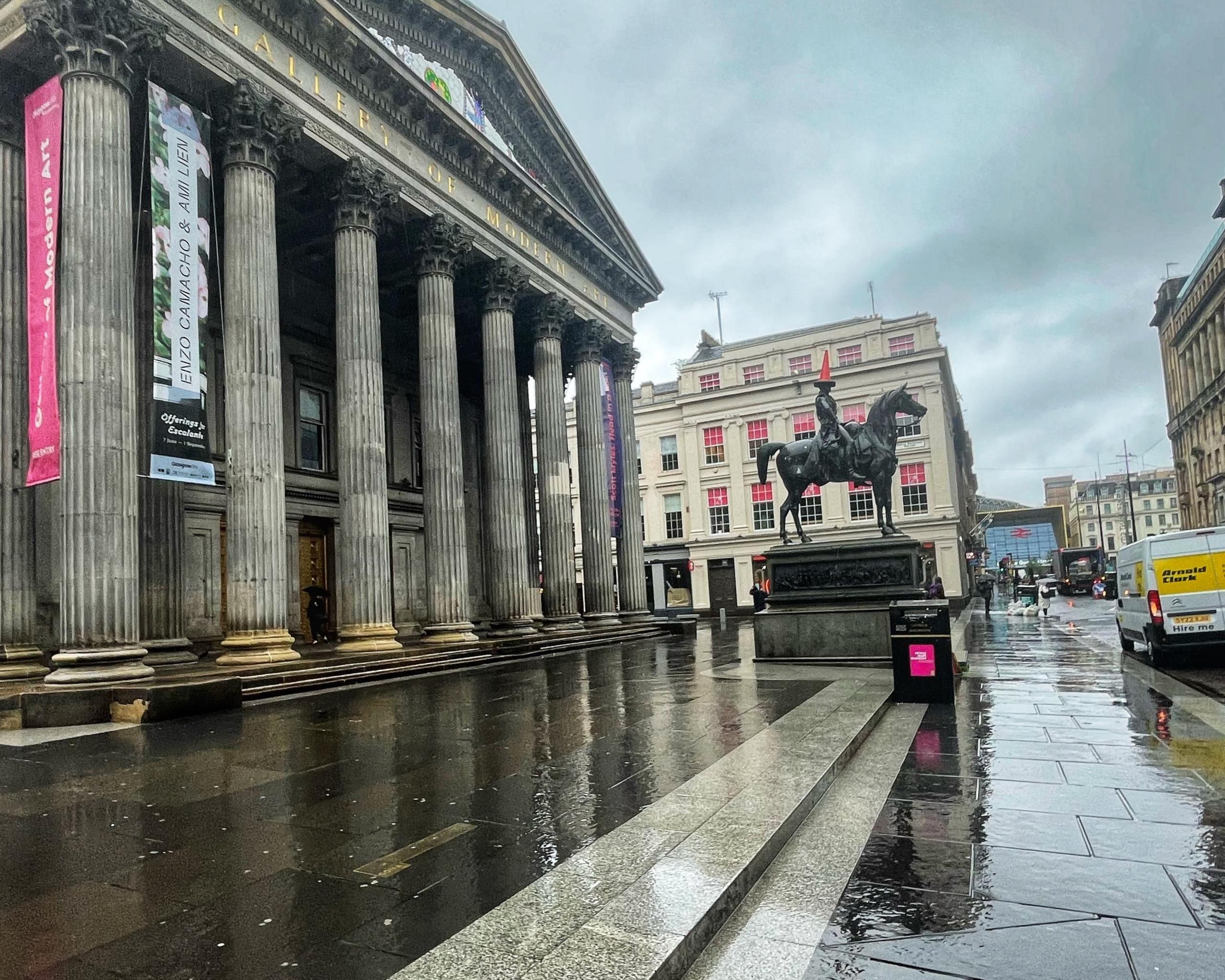 Very wet streets in Glasgow with the Wellington Statue in the background.