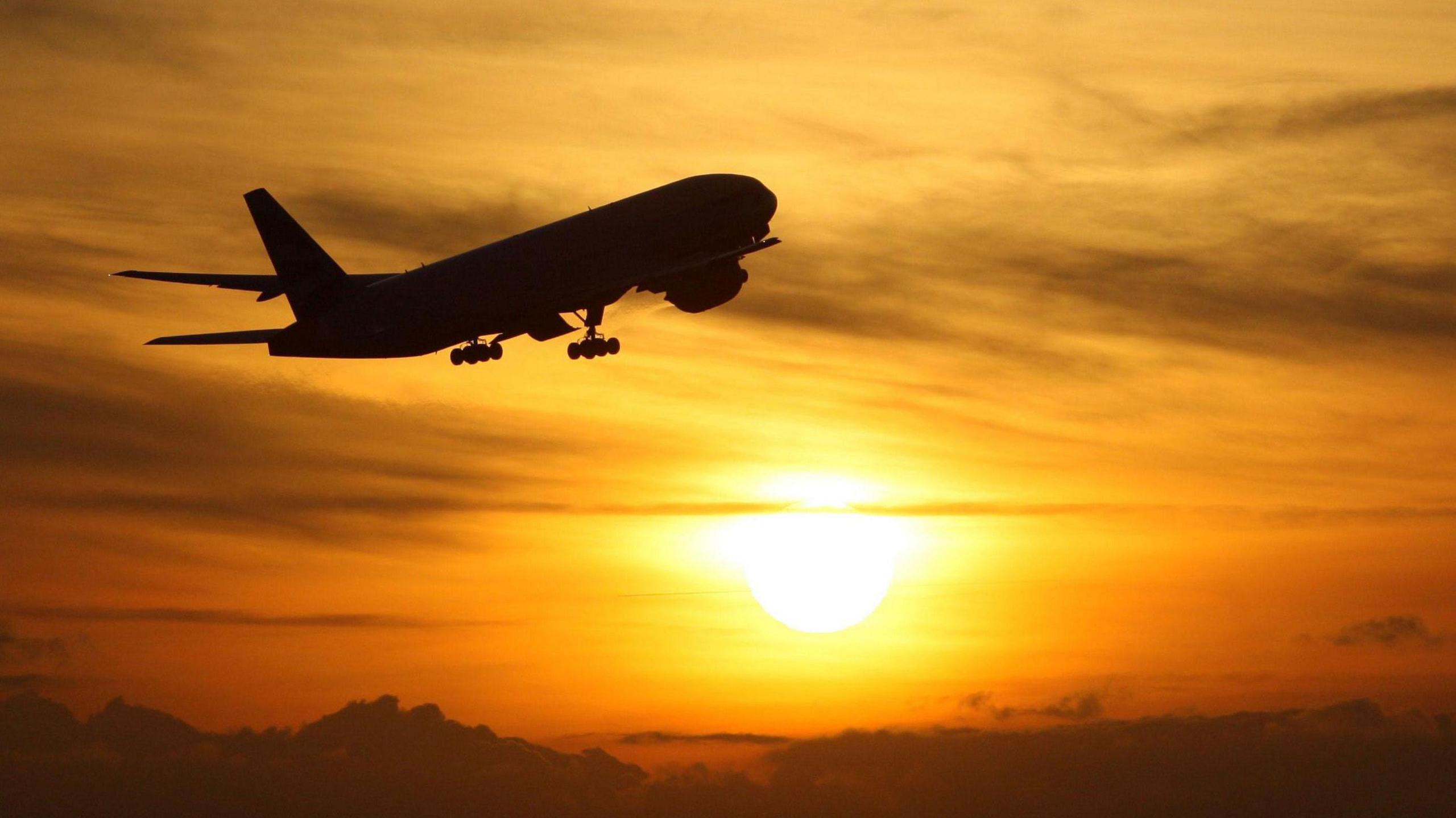 Plane ascending into sunset