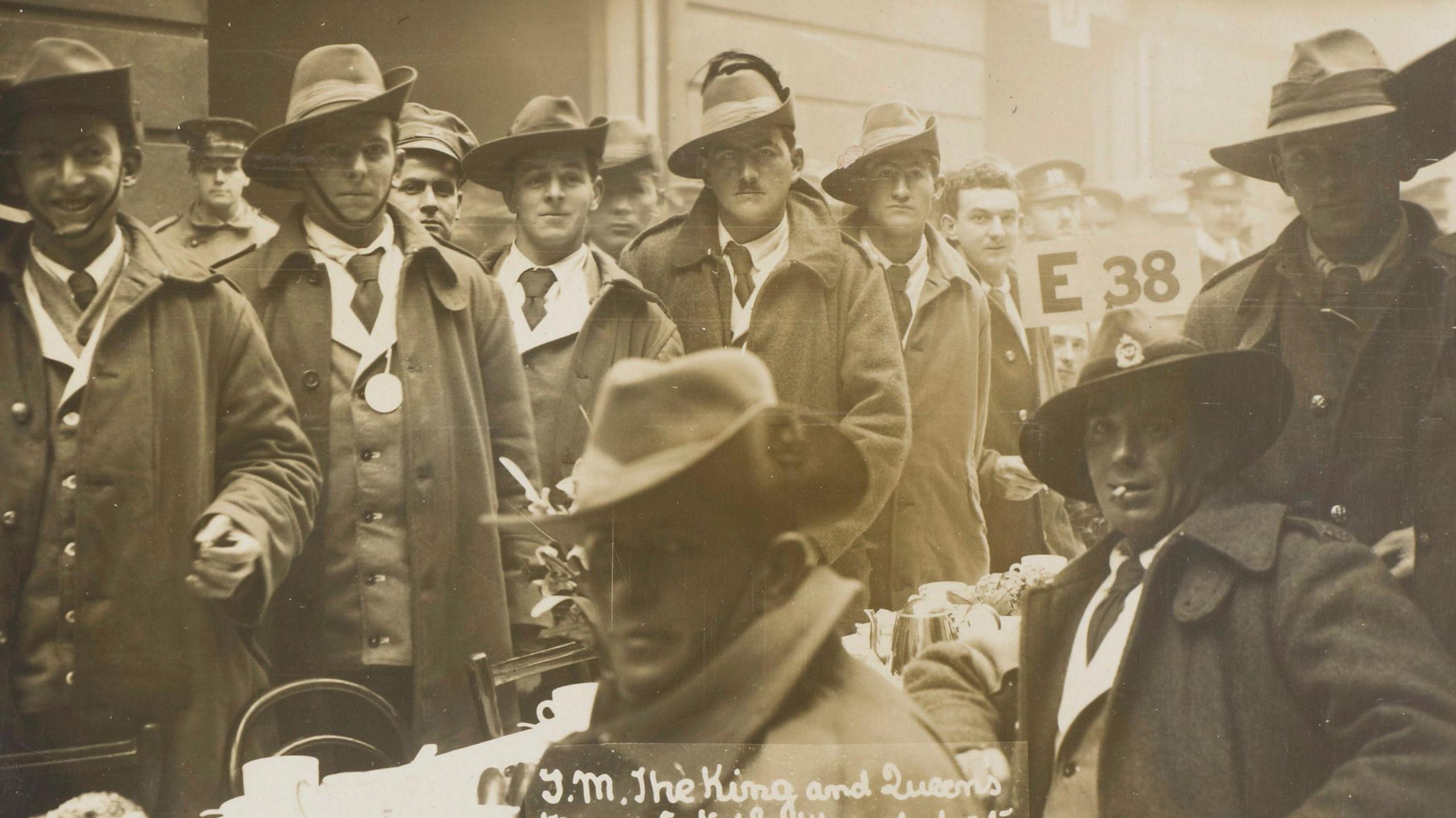 A black and white image of a group of World War One soldiers standing and sitting at tables in the Mews. 