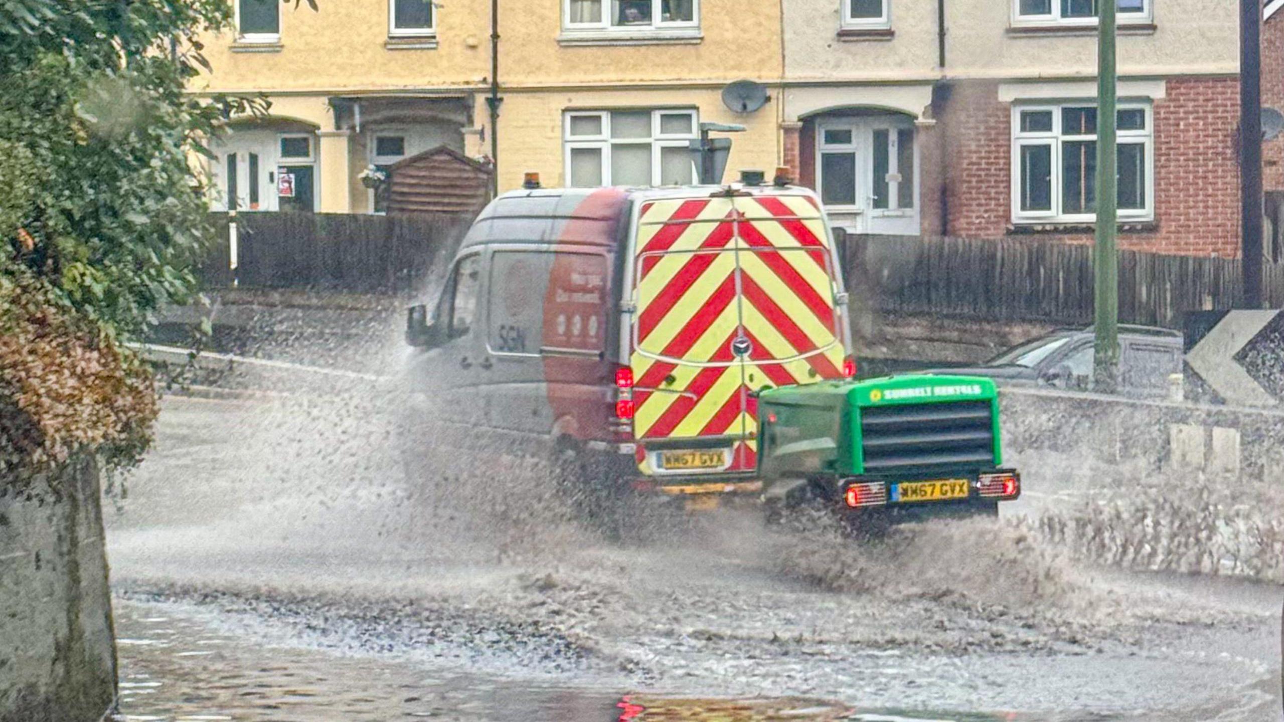 A van driving through a large puddle