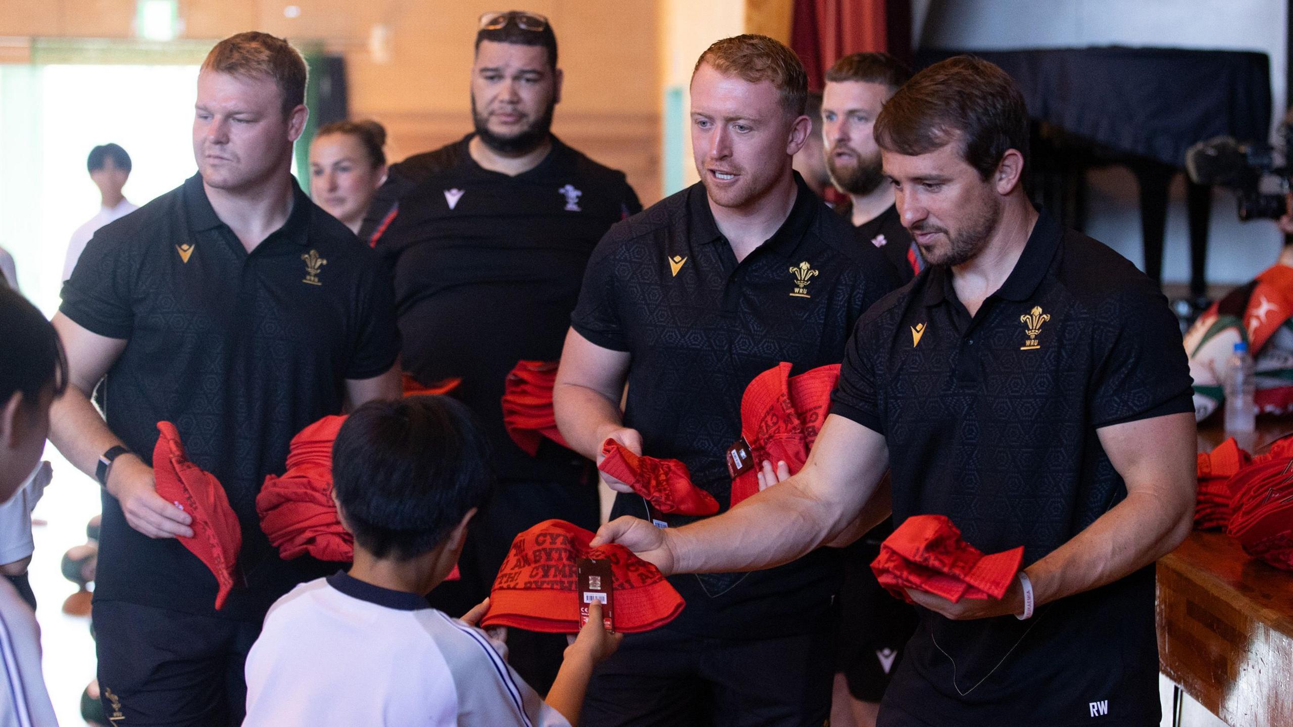 Wales trio Dewi Lake, Tommy Reffell and Rhodri Williams handing out gifts to Japan schoolchildren