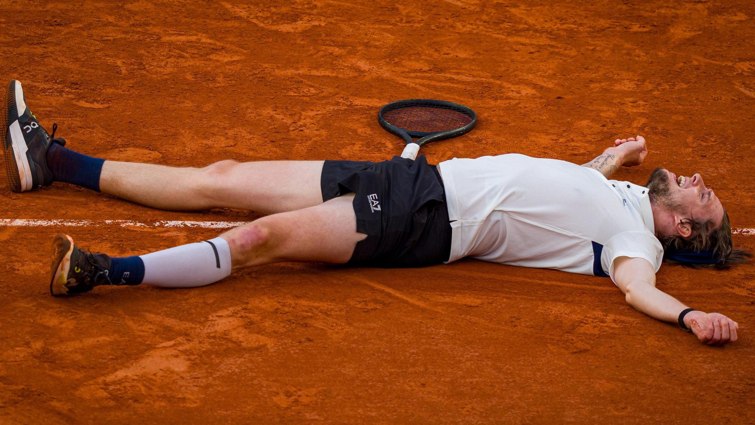Alexander Bublik lays on the ground after defeating Jack Draper at the French Open