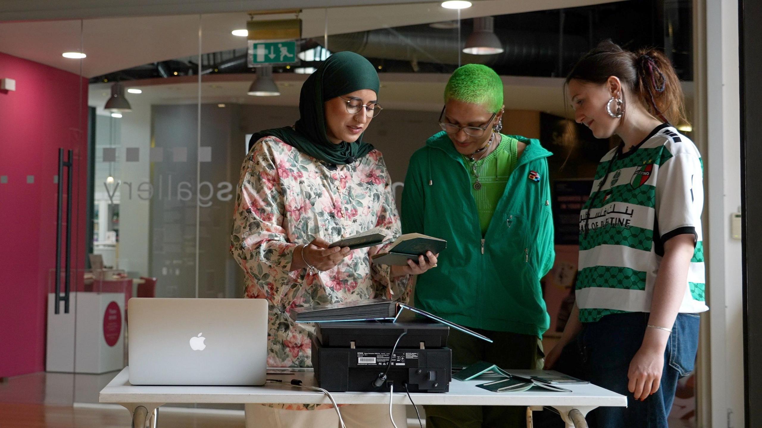 A group of three young people examining photographs