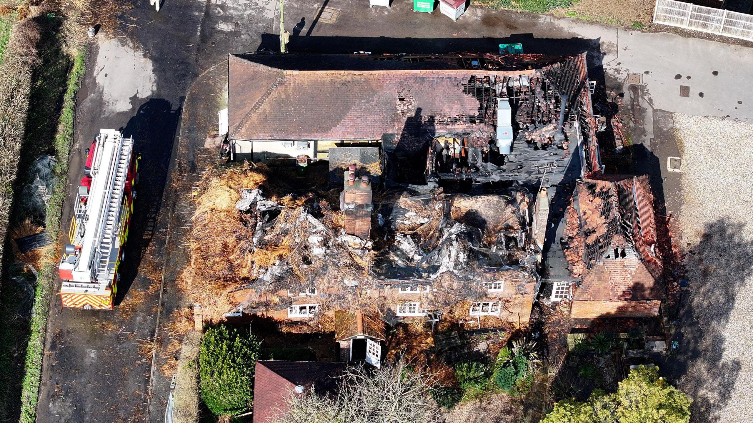 A destroyed pub building with a fire engine on the road to the left