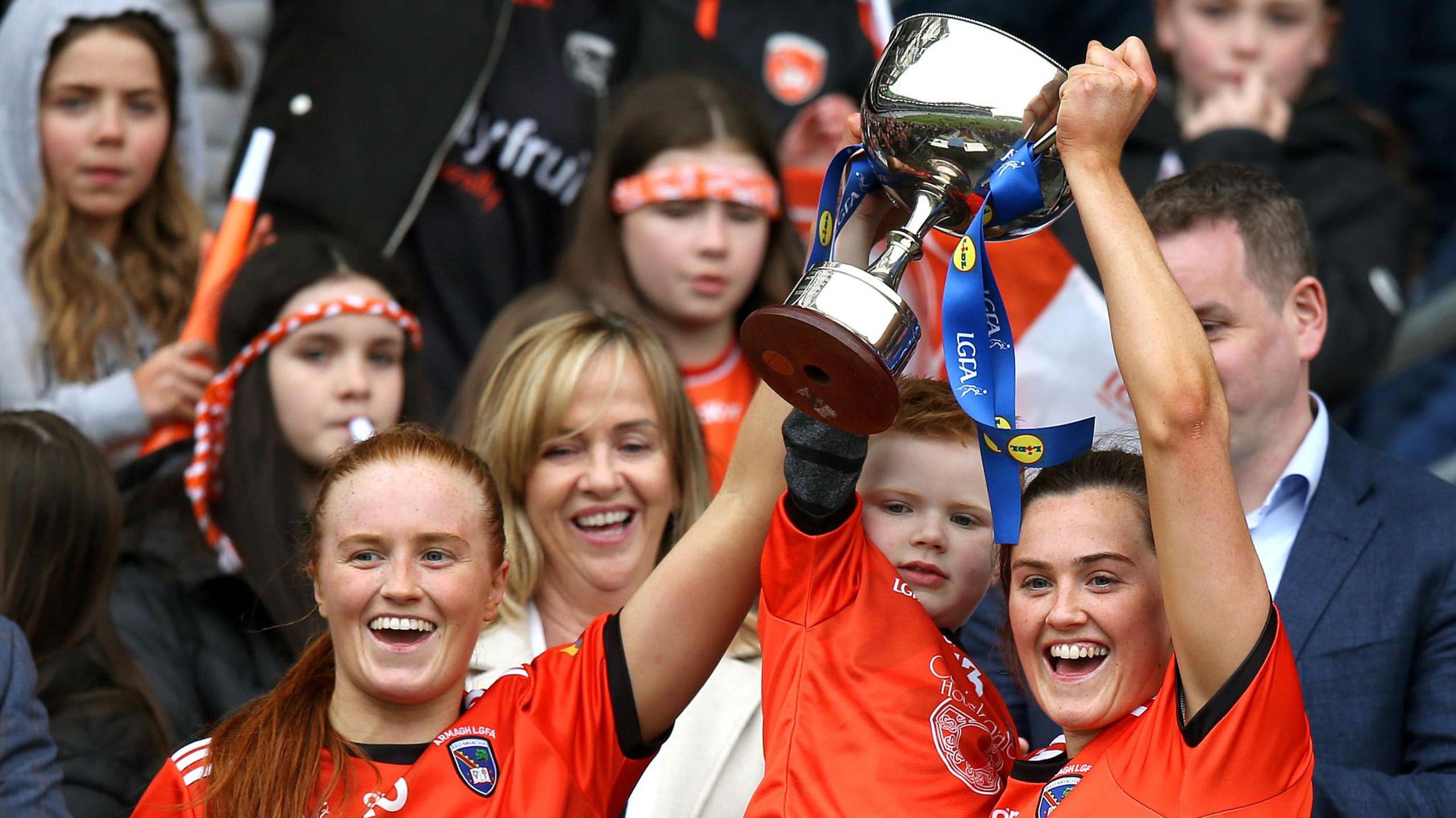 Sisters Blaithin and Aimee Mackin celebrate Armagh's Division Two League Final victory with nephew Fionn in 2023