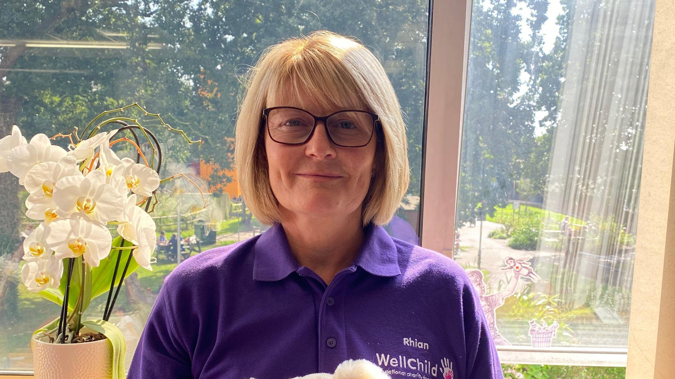 Rhian Greenslade smiling in WellChild polo shirt in hospital