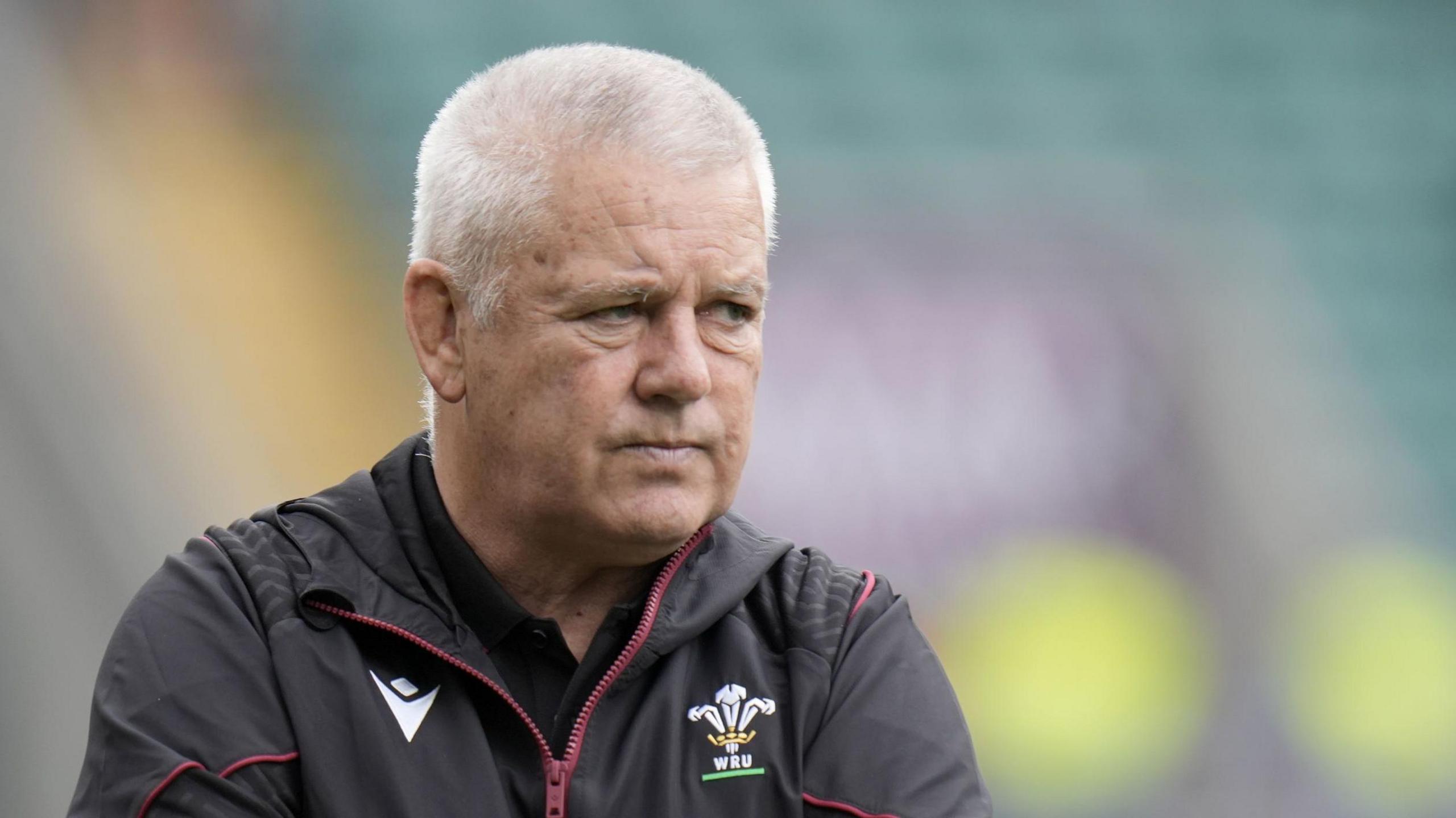 Warren Gatland, head coach for Wales rugby, stands on the pitch in a tracksuit.