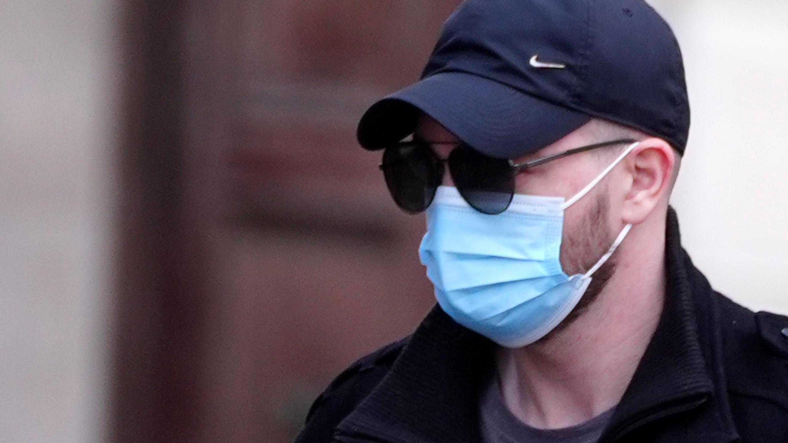 Kyle Shaw wearing a blue surgical face mask, black cap and black jacket and grey t-shirt arrives at Liverpool Crown Court