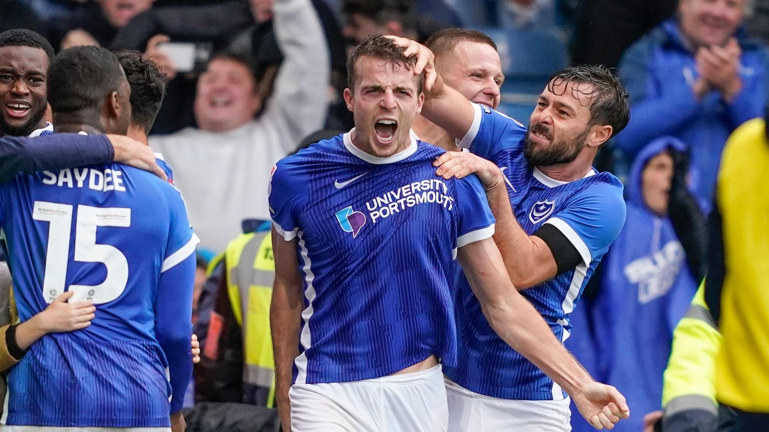 Conor Shaughnessy celebrates with Joe Rafferty after scoring a goal for Pompey, while Christian Saydee watches on.