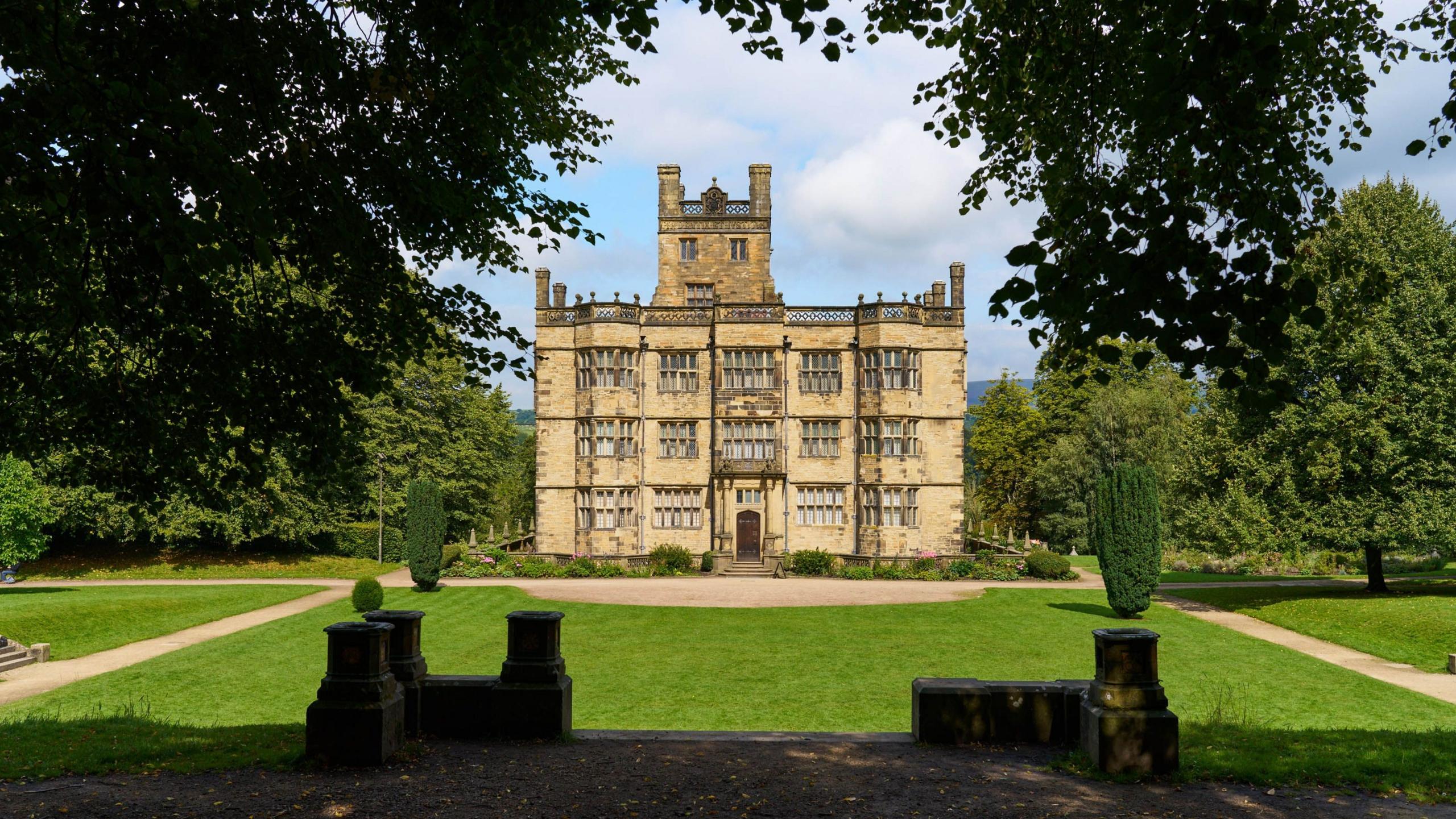 Gawthorpe Hall, a square stone building standing on a large lawn with trees either side