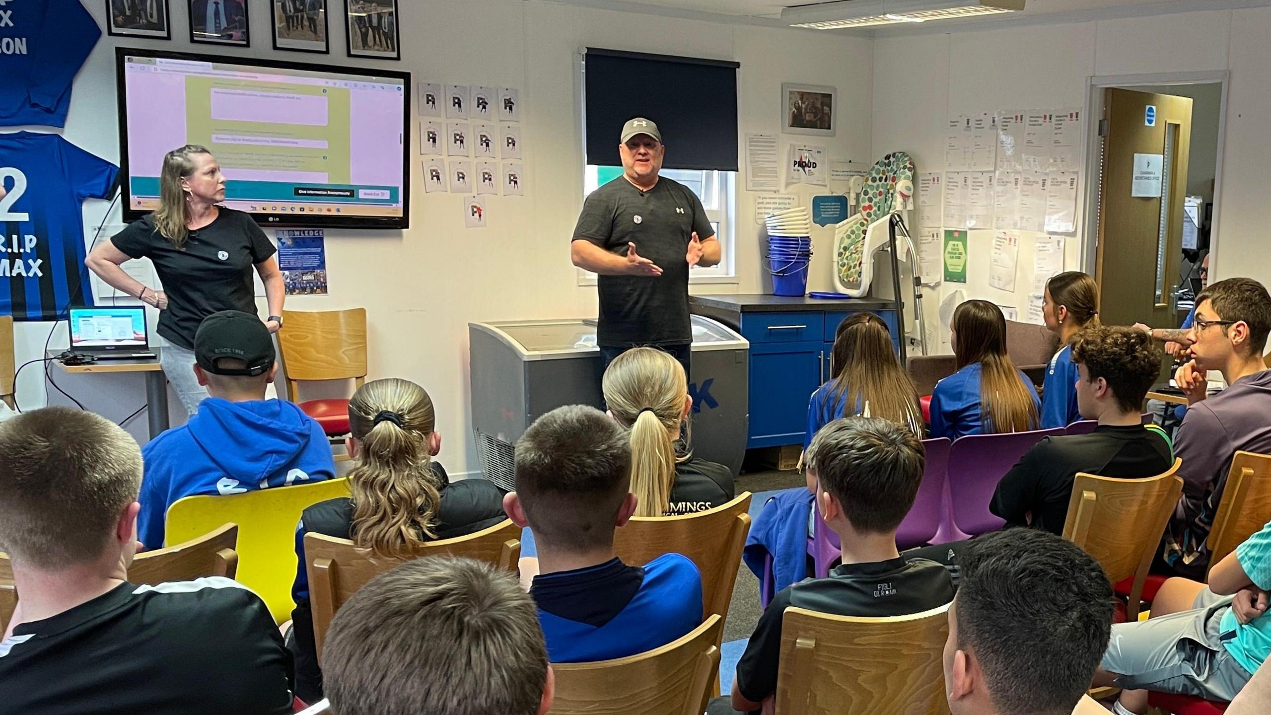 Young people sat in a room listening to a workshop on how to use bleed kits