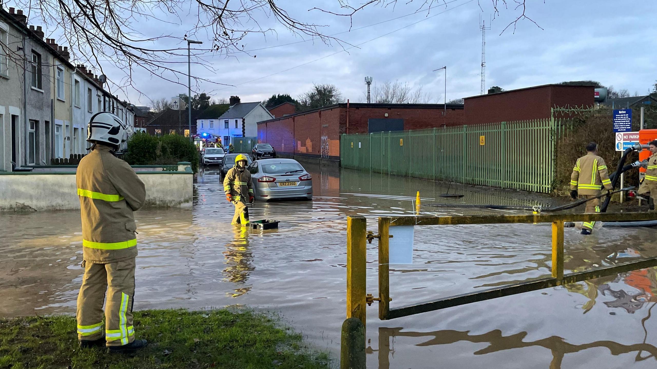 Firefighters work in a flooded areas in a area of houses