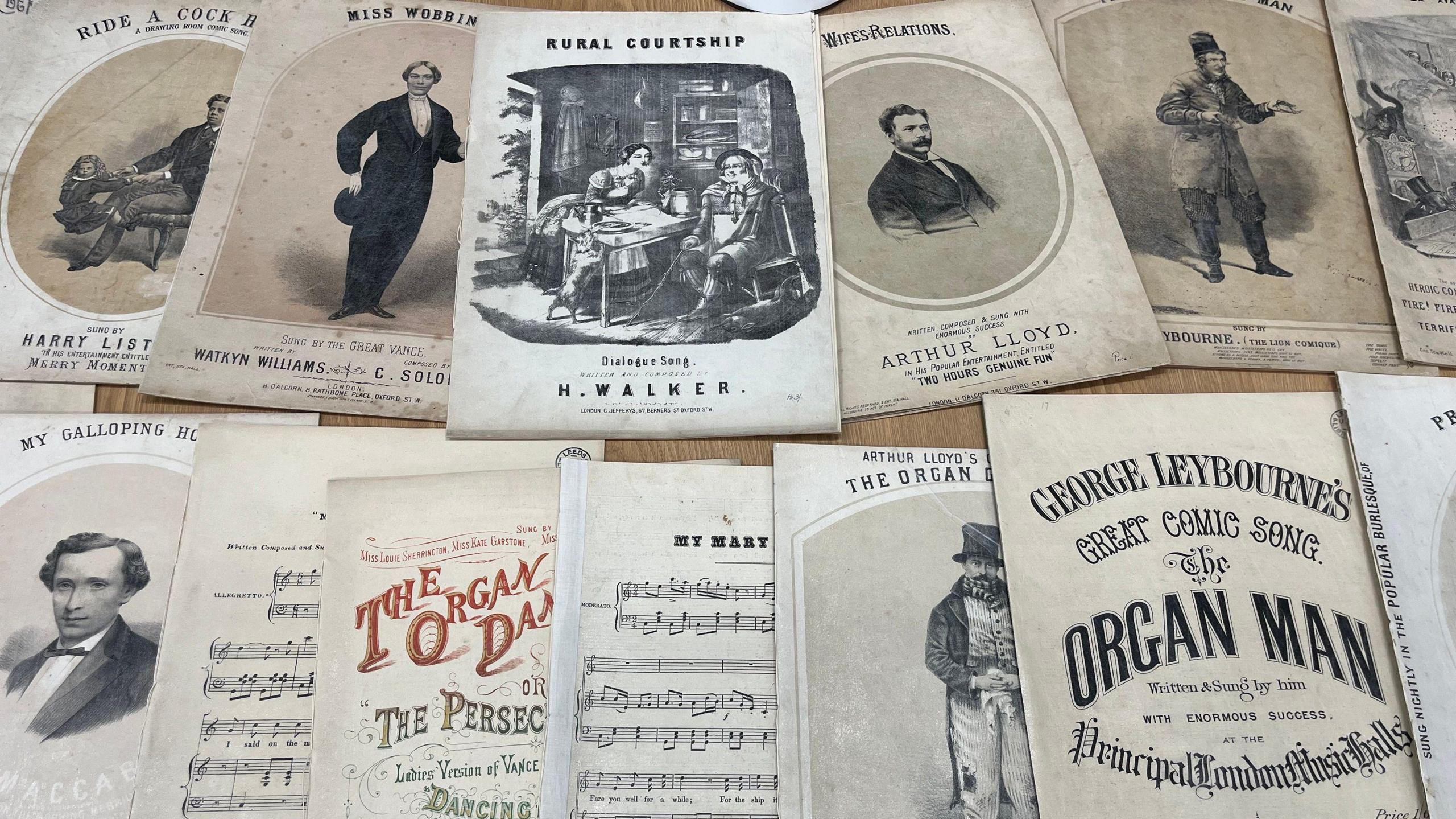 A selection of Victorian sheet music pamphlets with images of men in suits.