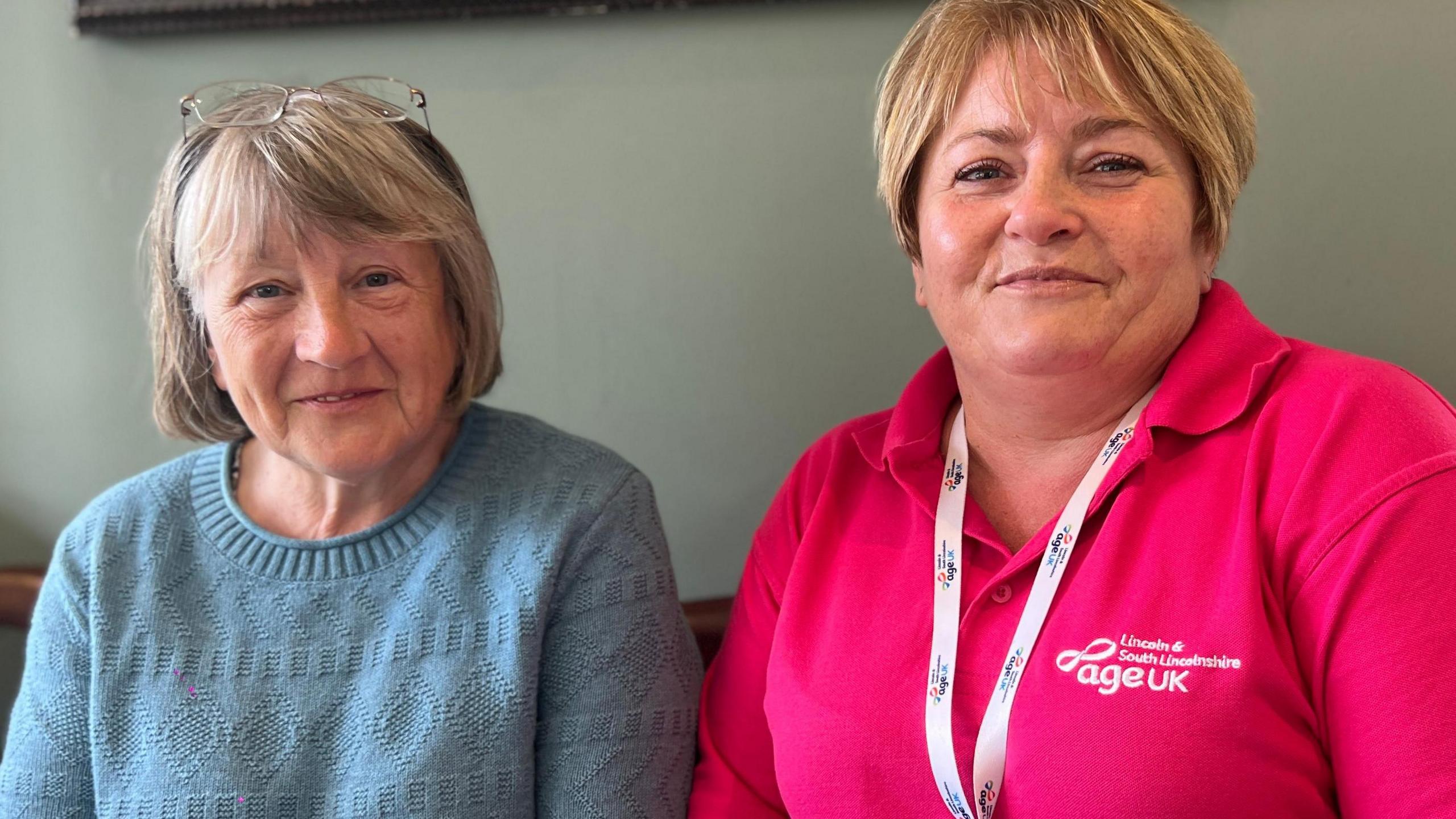 Elaine Smith is to the left of the frame in a blue jumper and has a blonde bob. Her glasses are perched on top of her head. To her right is 
Amanda Palser, from Age UK Lincoln and South Lincolnshire. Amanda is in a bright pink t-shirt and is smiling.