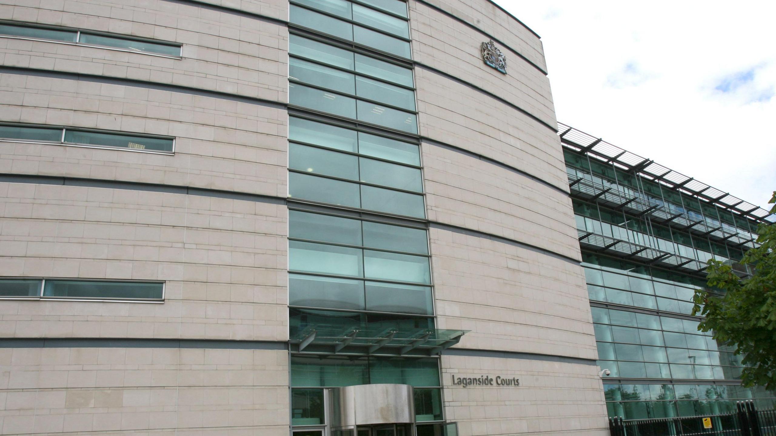 Laganside courthouse in Belfast with white brick walls and glass panels. The sky is cloudy and grey