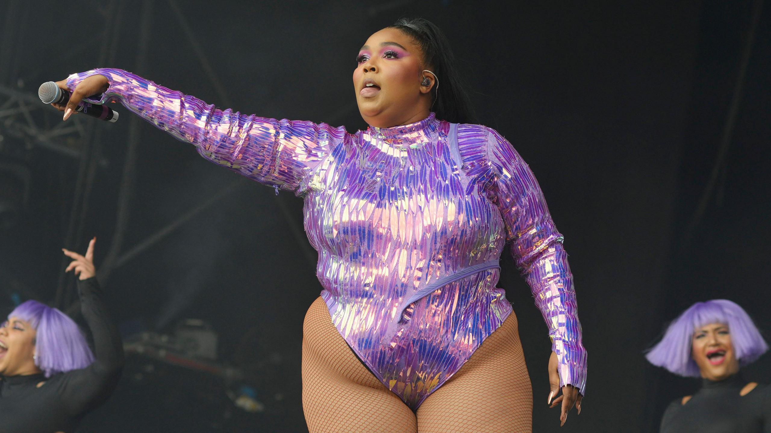 Lizzo pictured wearing a sparkly purple outfit while performing at Glastonbury Festival in 2019