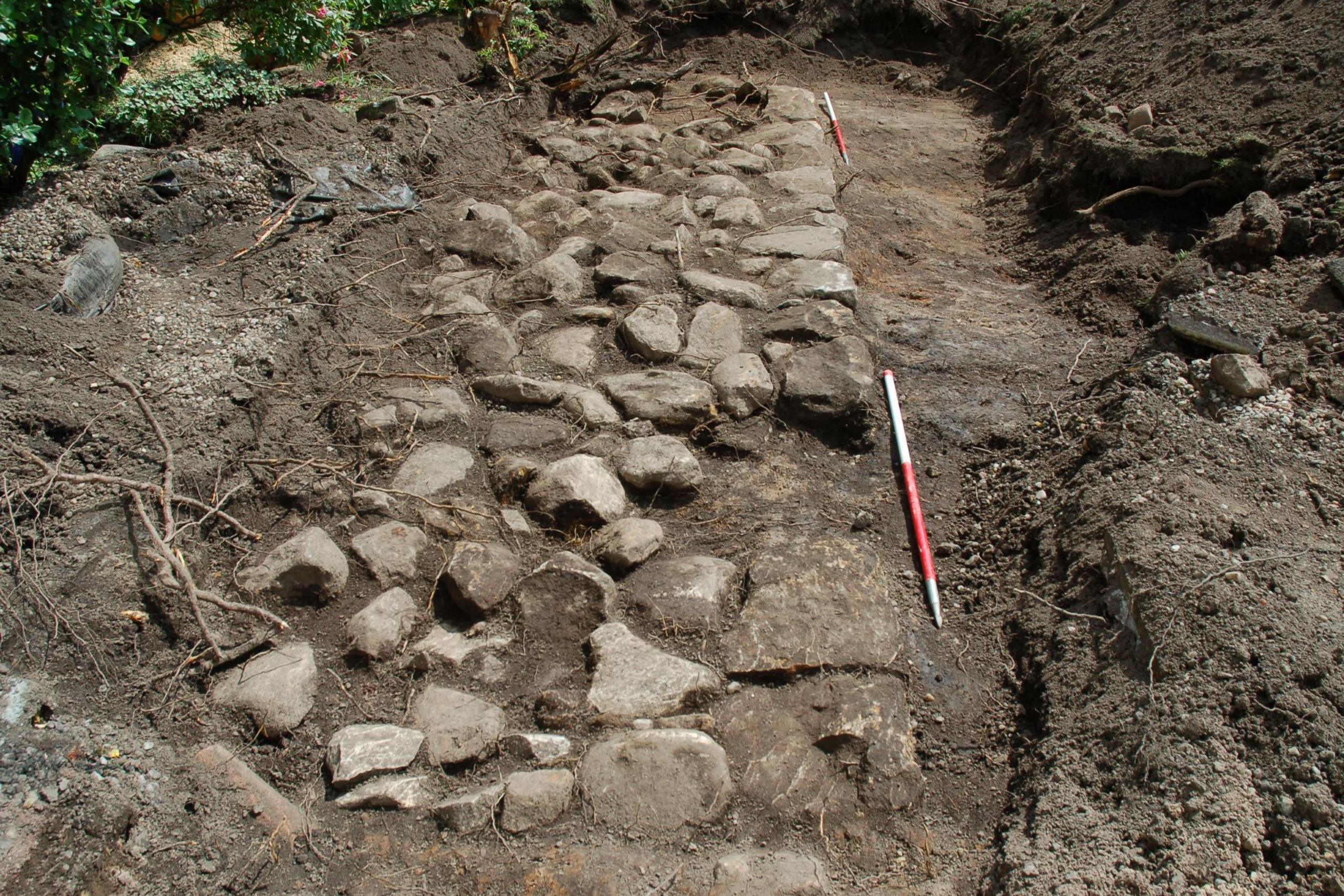 The foundations look like a cobbled path. The stones are in an area of exposed ground and there are areas of soil around it.