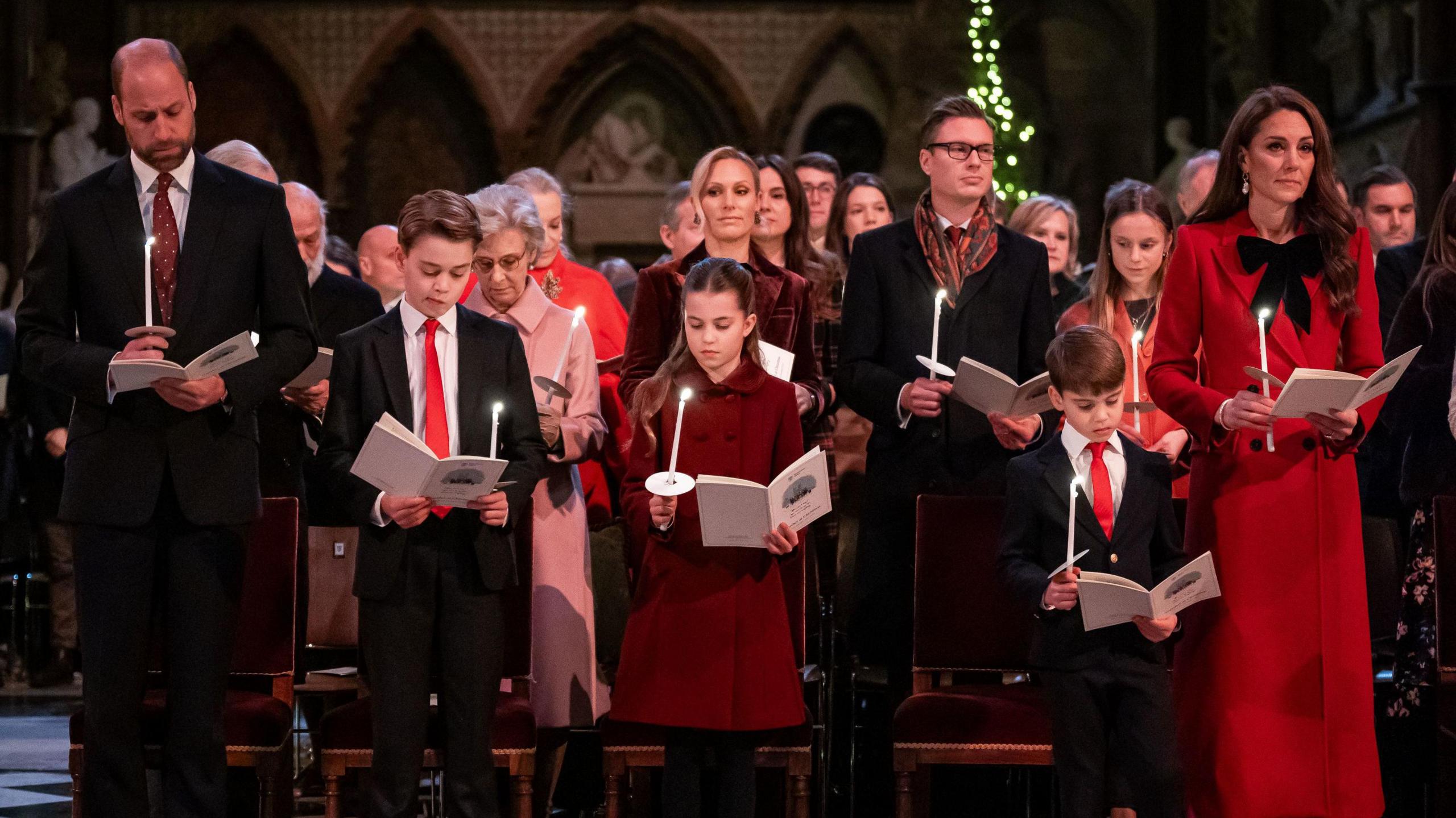 (left to right) Prince William, Prince George, Princess Charlotte, Prince Louis, and Princess Catherine standing in Westminster Abbey during the carol service. They are at the front and rows of people behind them.